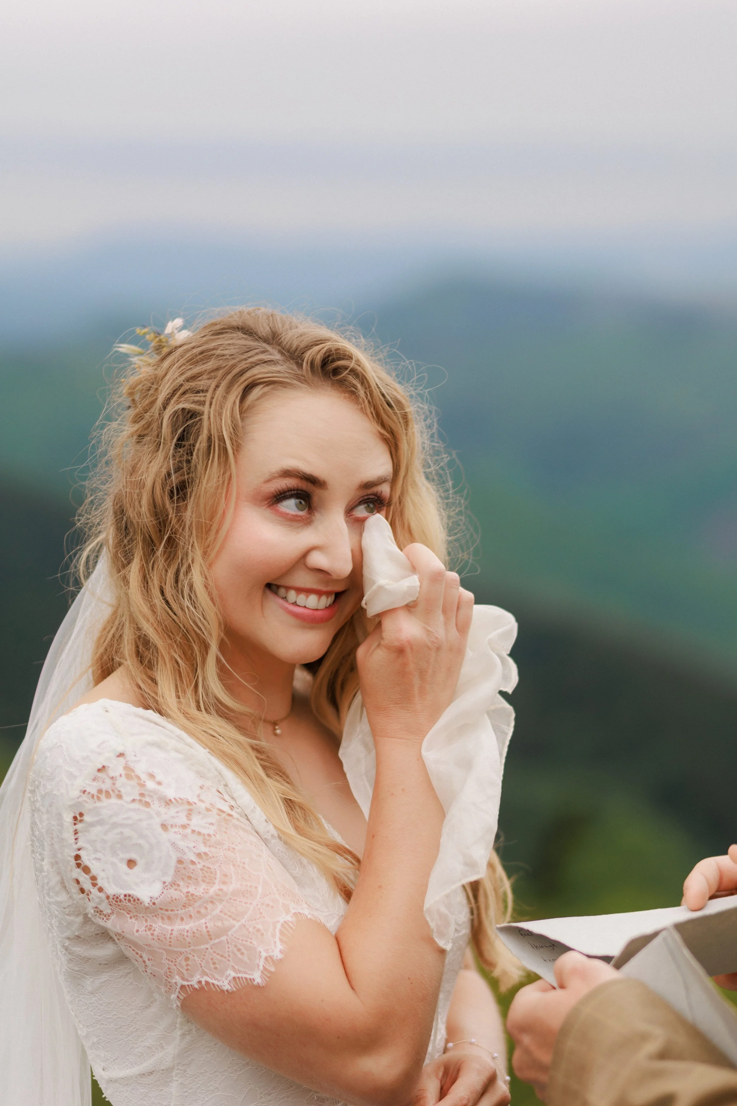 A bride patting a tear from her eye.