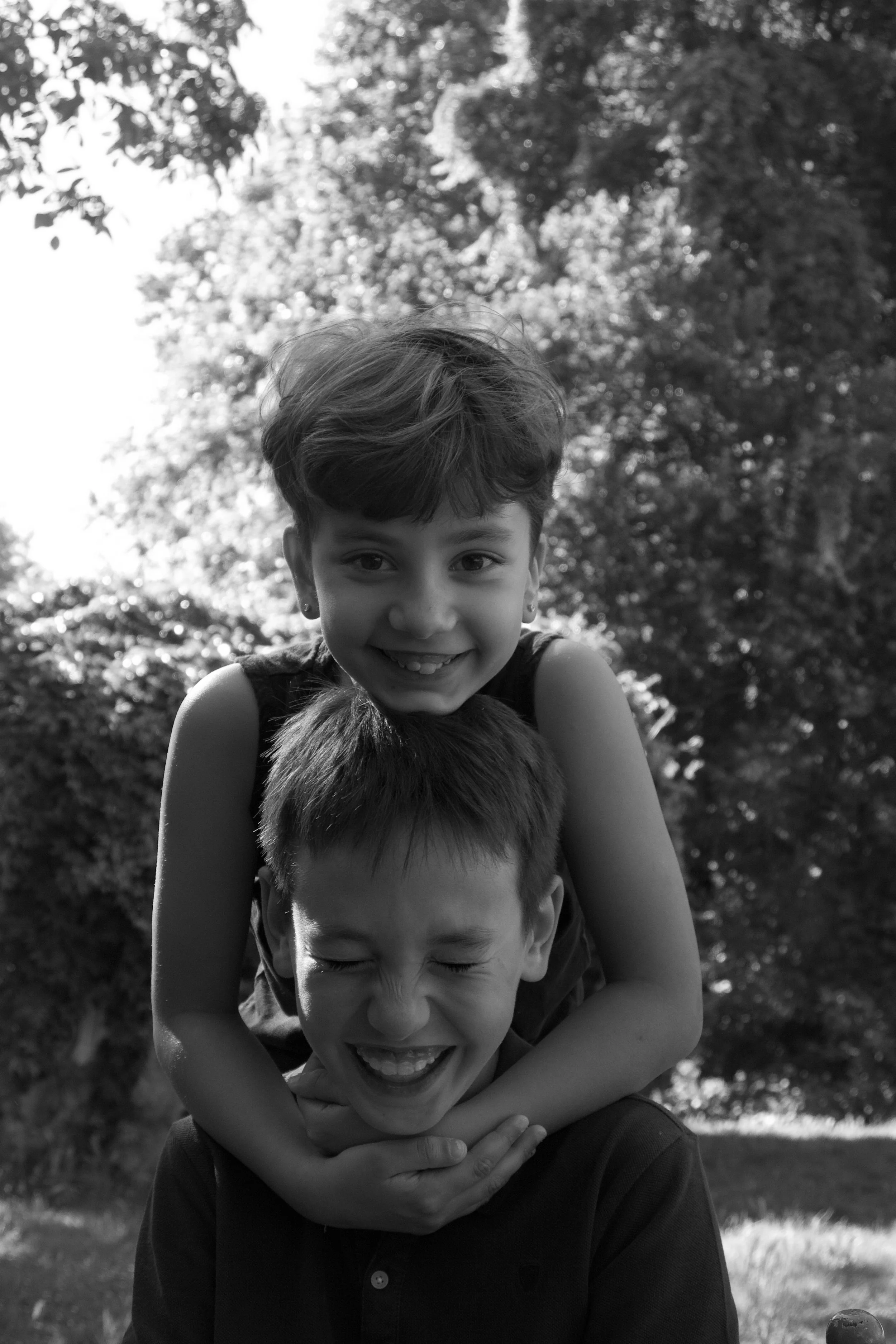 Close-up candid portrait of two siblings sharing a funny moment, capturing genuine laughter and an easy, affectionate connection.