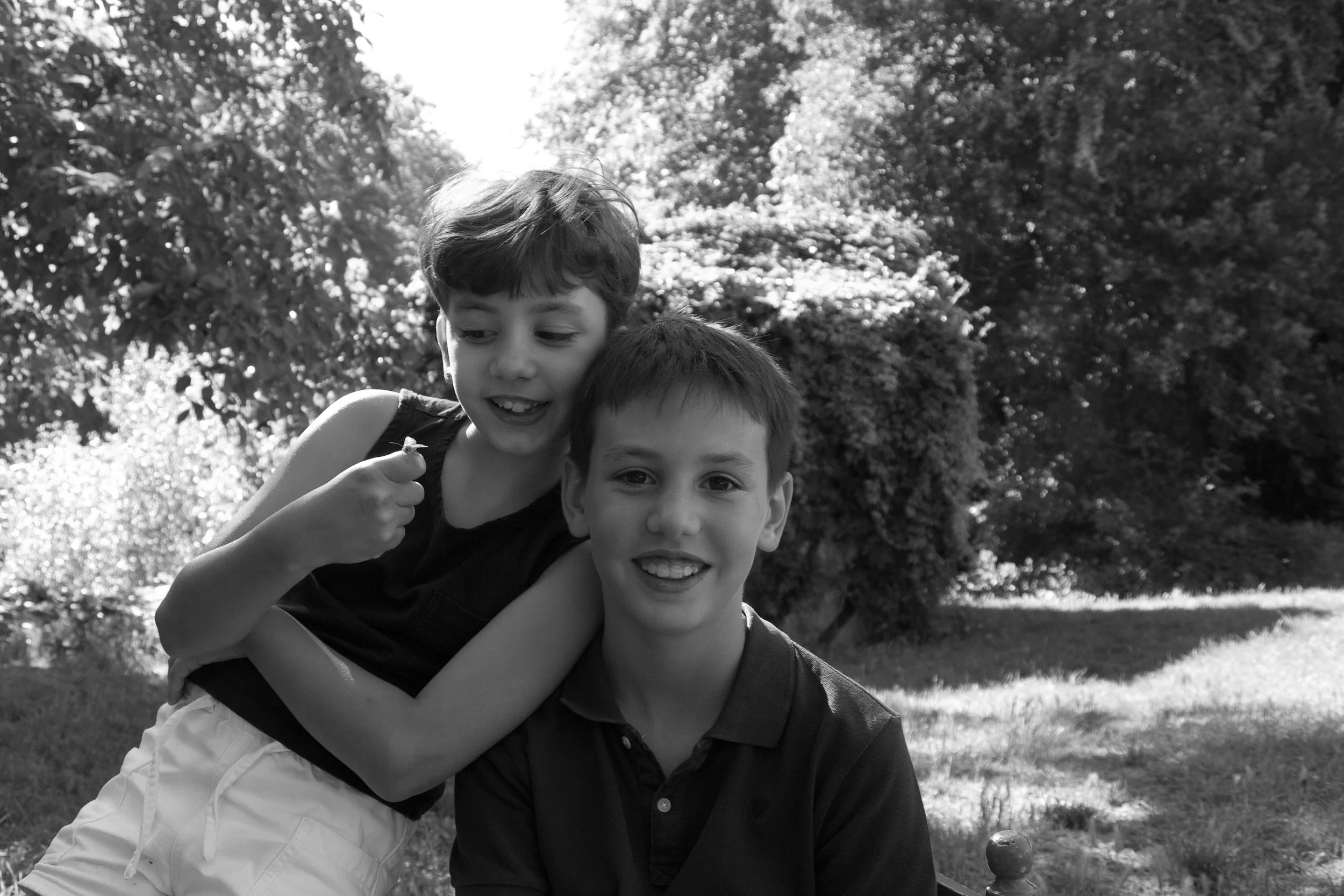 Candid children’s photography capturing two siblings laughing and playing together in a relaxed outdoor family portrait session.