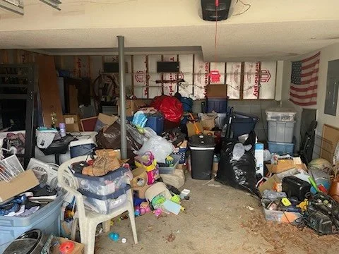Cluttered garage with random tools, boxes, and household items
