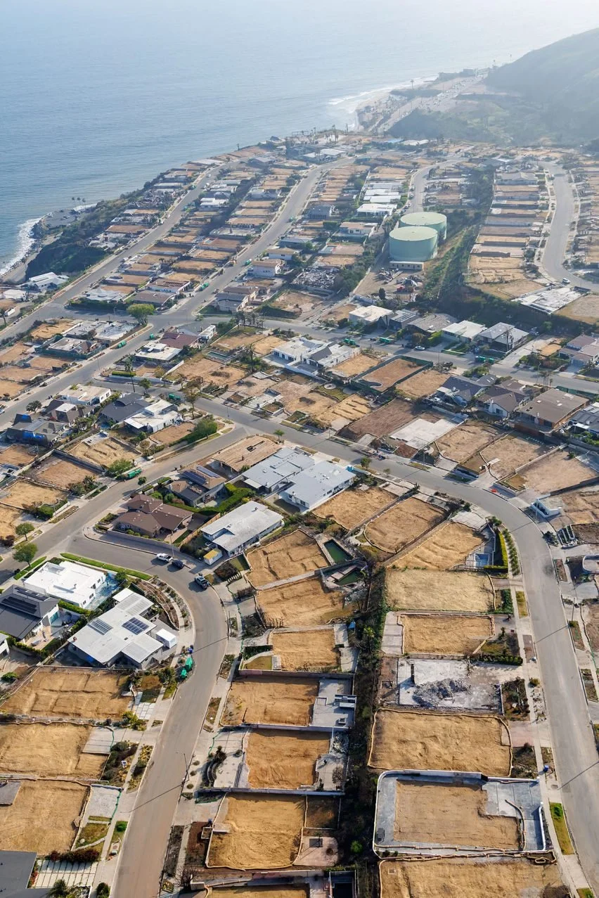 Aerial view of a coastal residential neighborhood with vacant lots, houses, and winding roads along the shoreline.