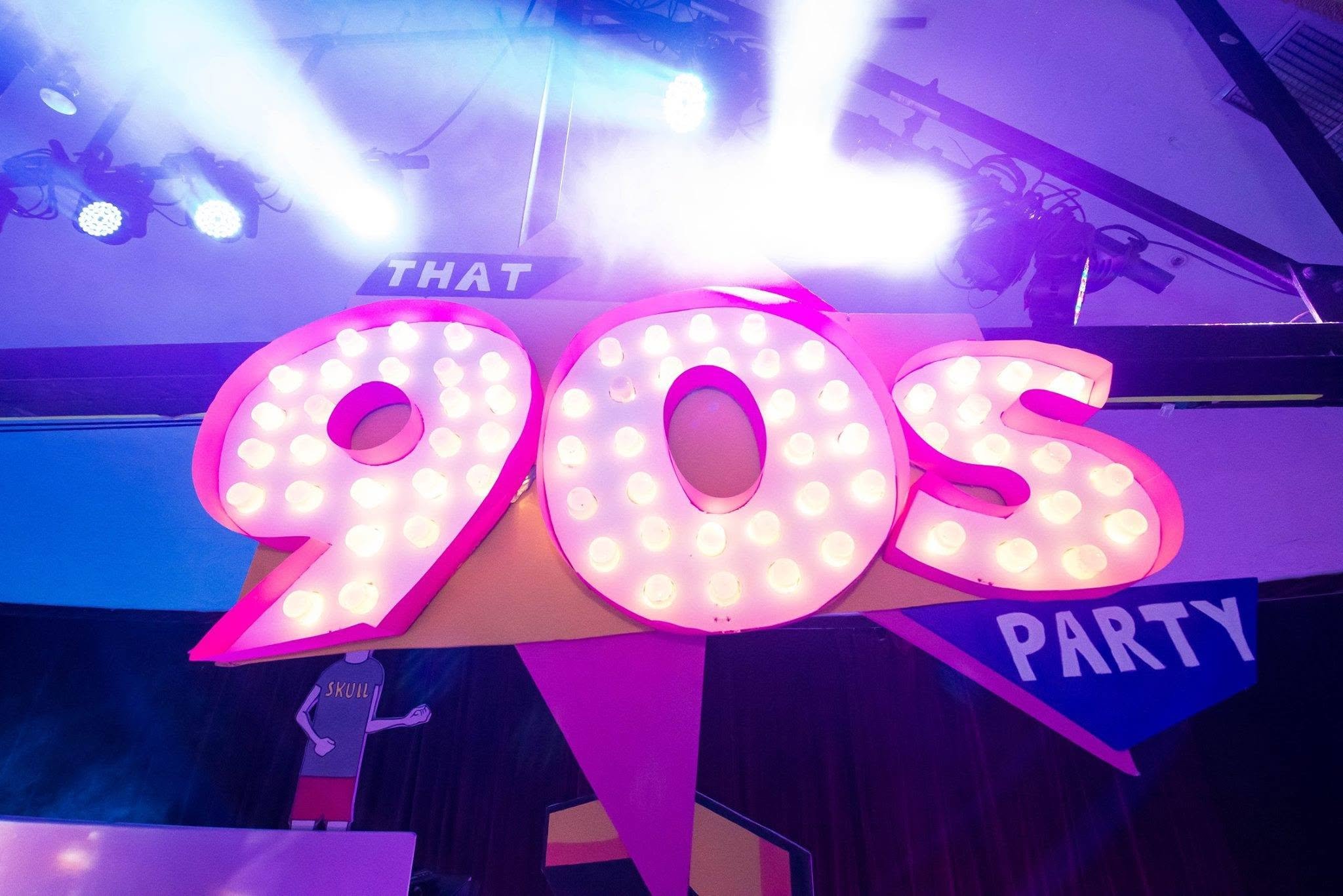 Brightly lit pink and white sign with the number '20' and the word 'Party'. Overhead blue and white lighting, with parts of a ceiling and other decorations visible in the background.