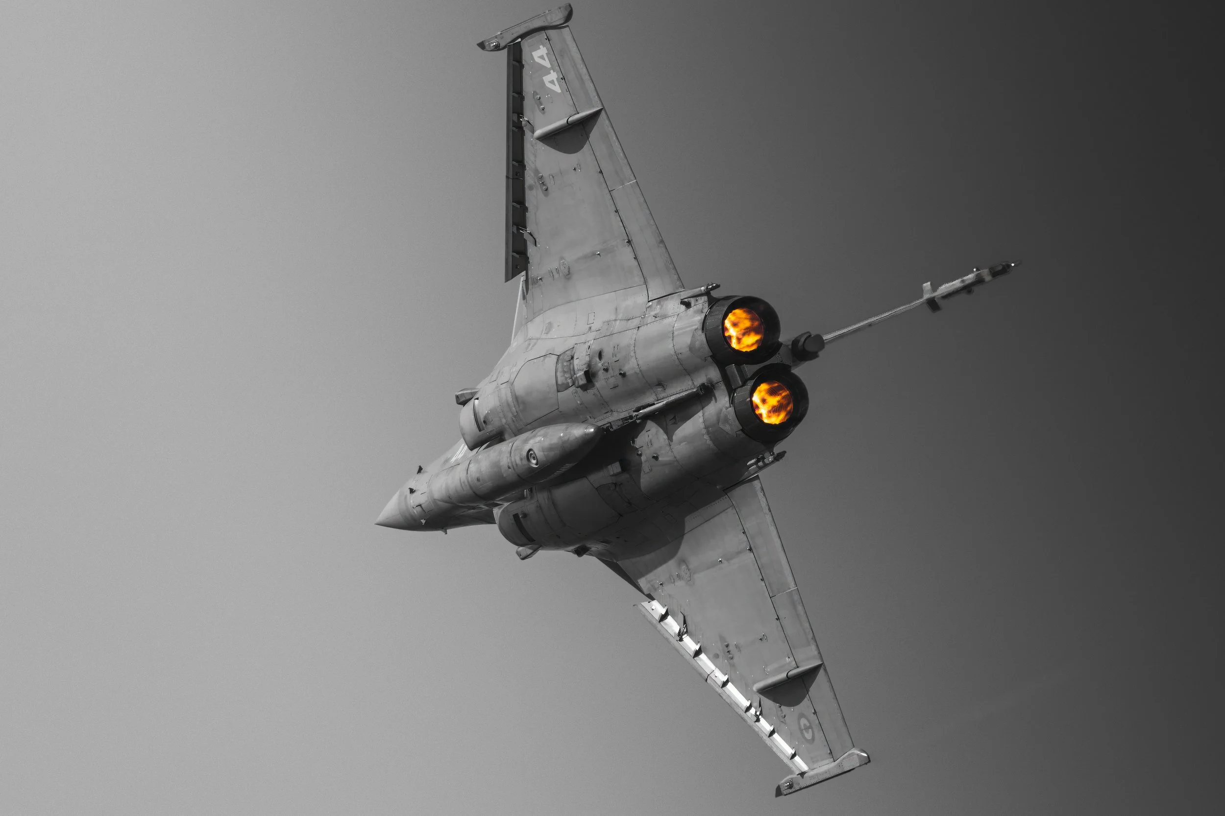 Un avion de chasse en vol avec des moteurs en feu, vu du dessous.
