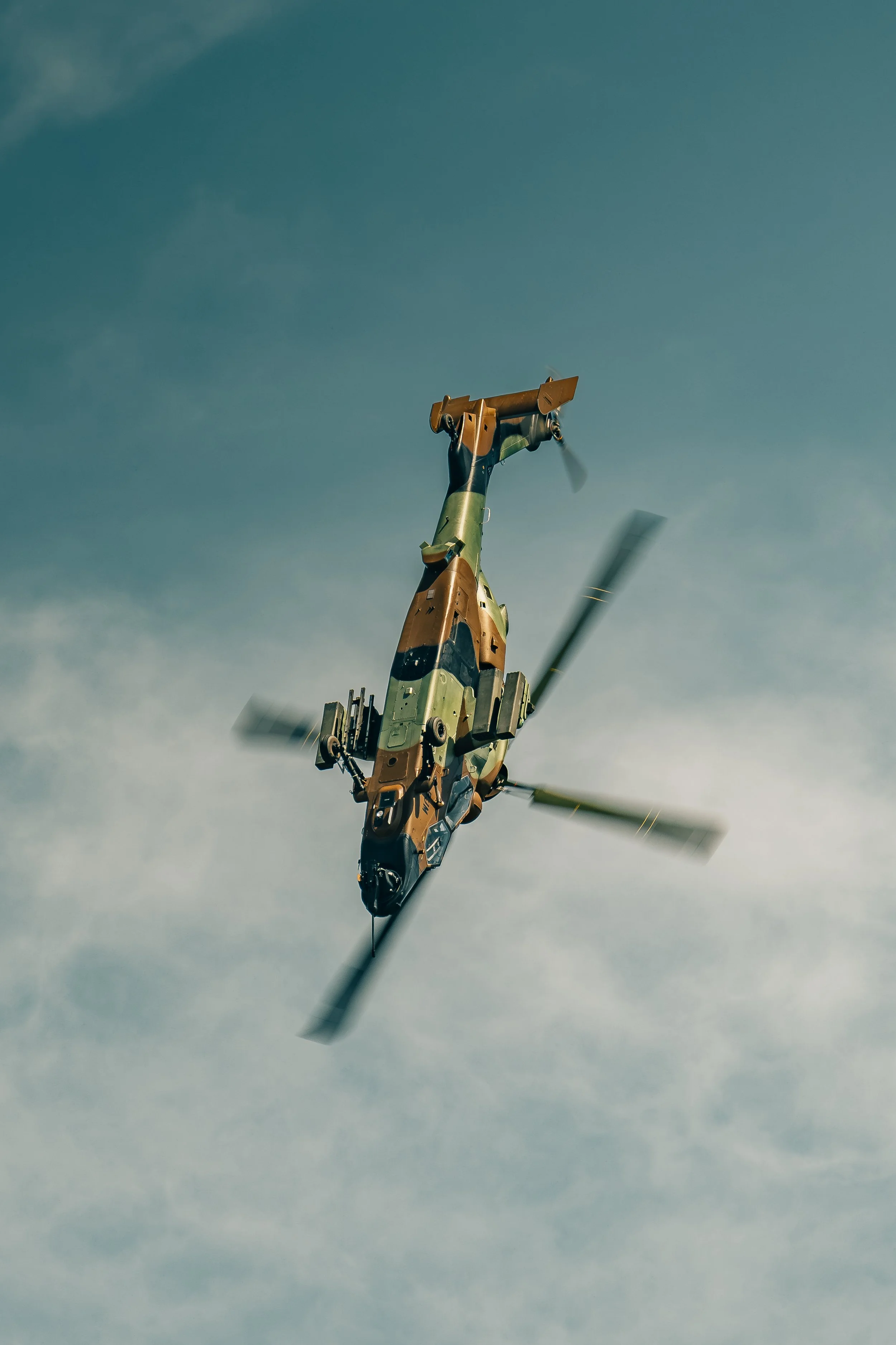Un hélicoptère de combat en vol dans le ciel, vue de dessous avec rotor en rotation.