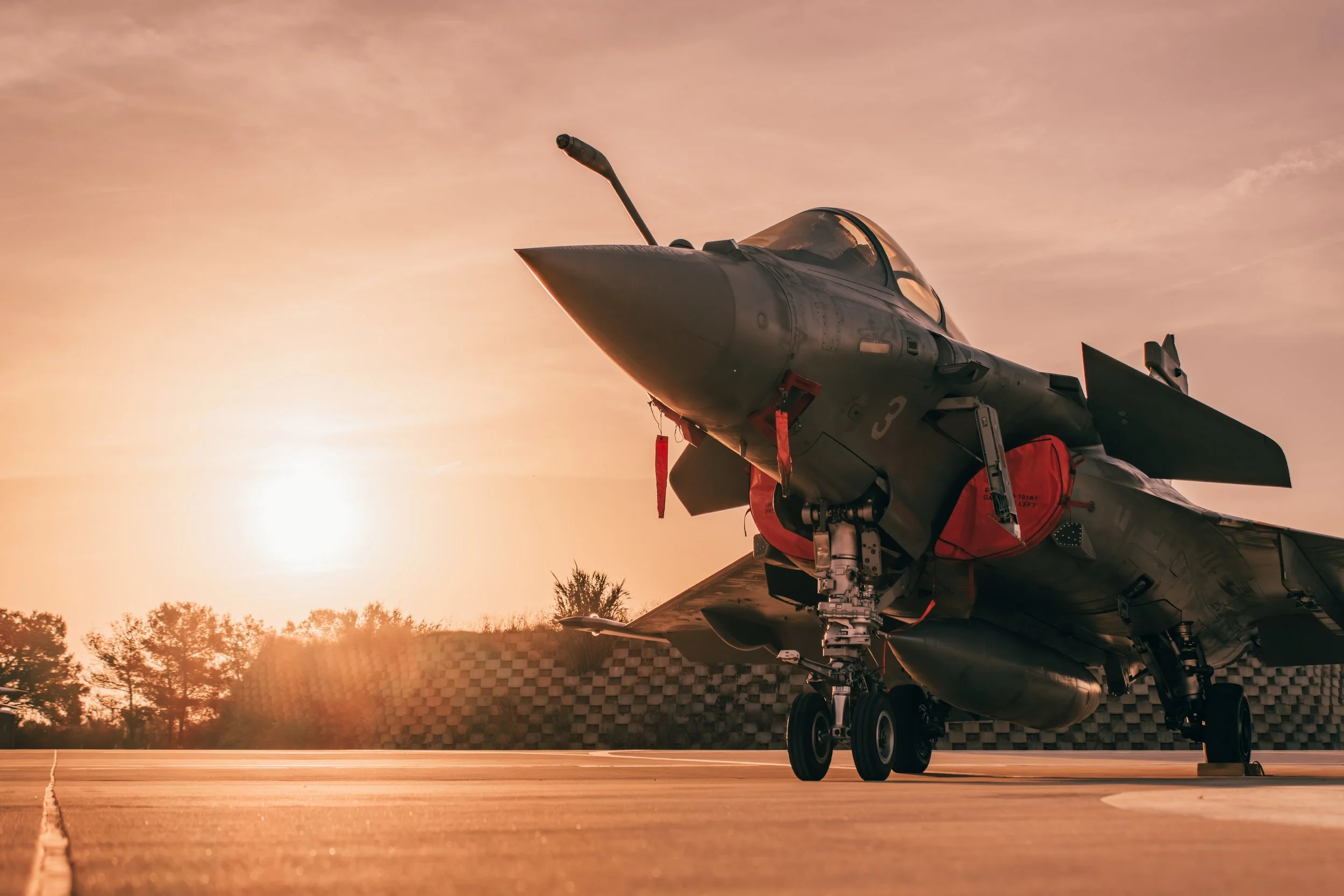 Un avion de chasse à l'arrêt au sol lors du coucher de soleil.