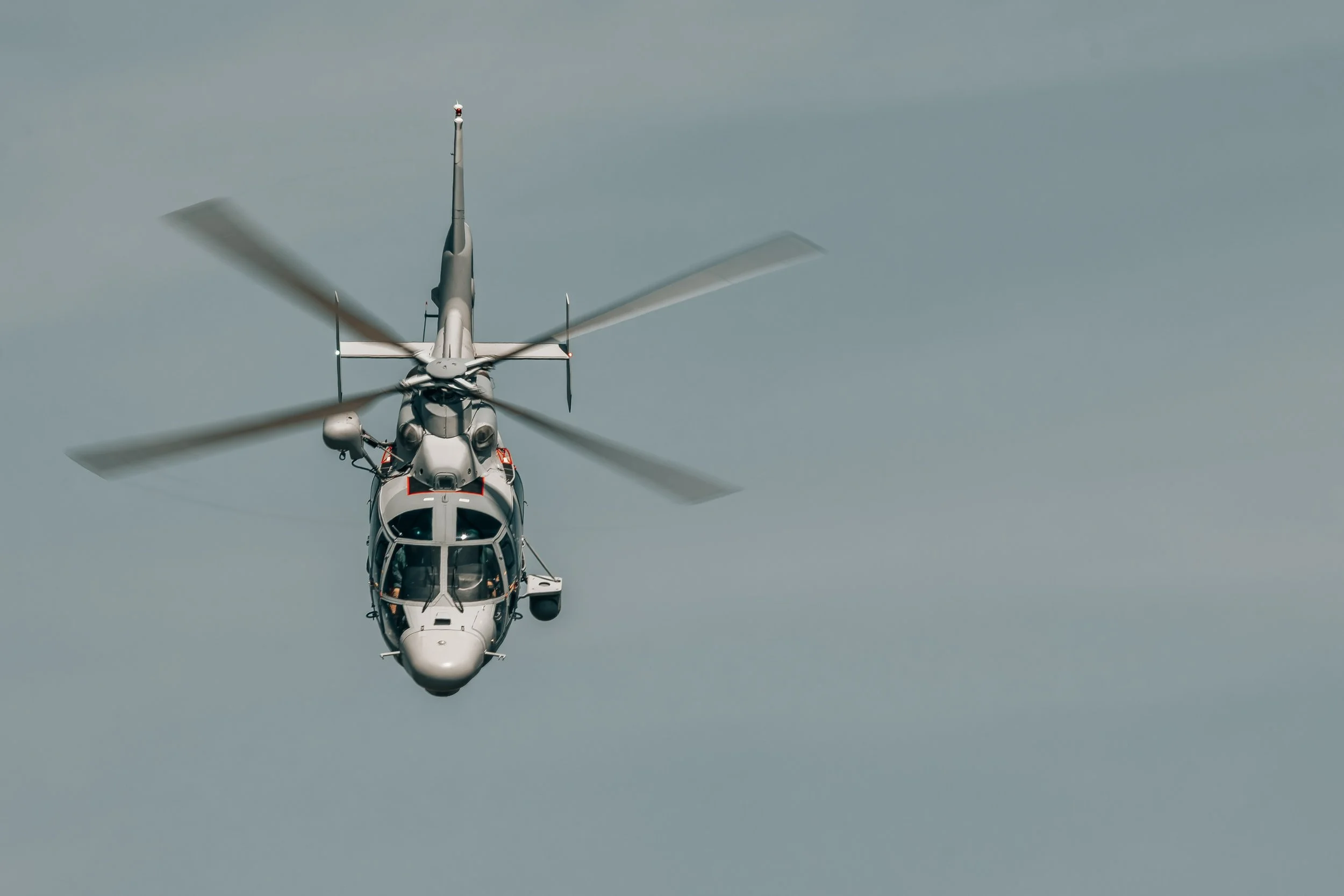 Un hélicoptère blanc volant dans le ciel avec des pales en mouvement.