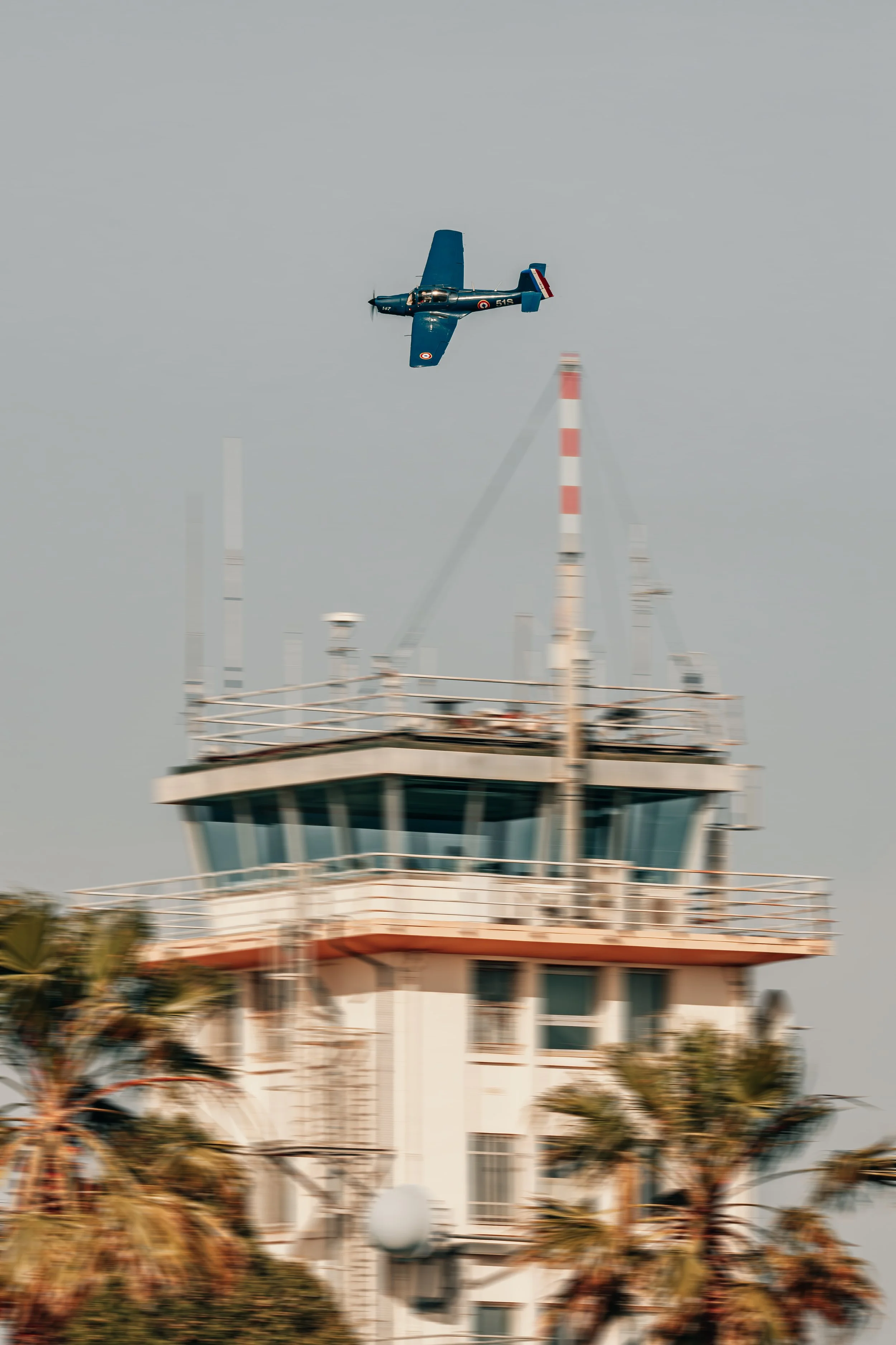 Un avion militaire vole au-dessus d'une tour de contrôle à un aéroport.