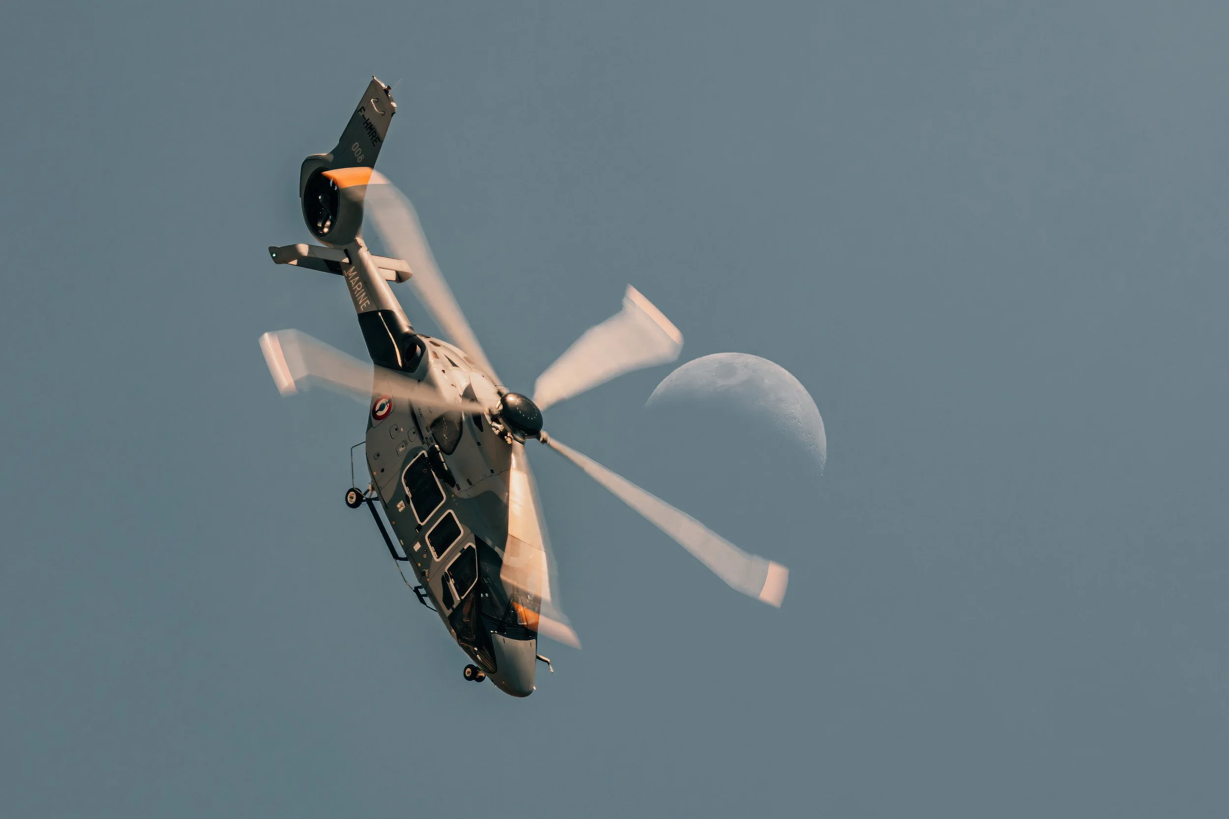 Un hélicoptère en vol à proximité de la lune dans un ciel clair.