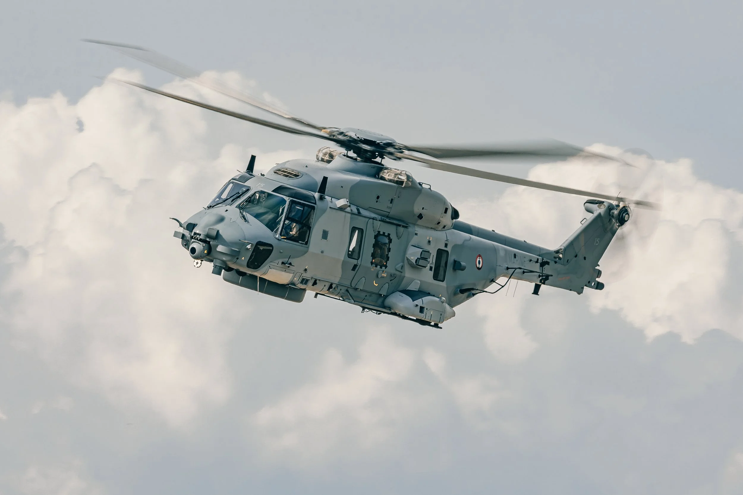 Un hélicoptère militaire en vol dans un ciel nuageux.