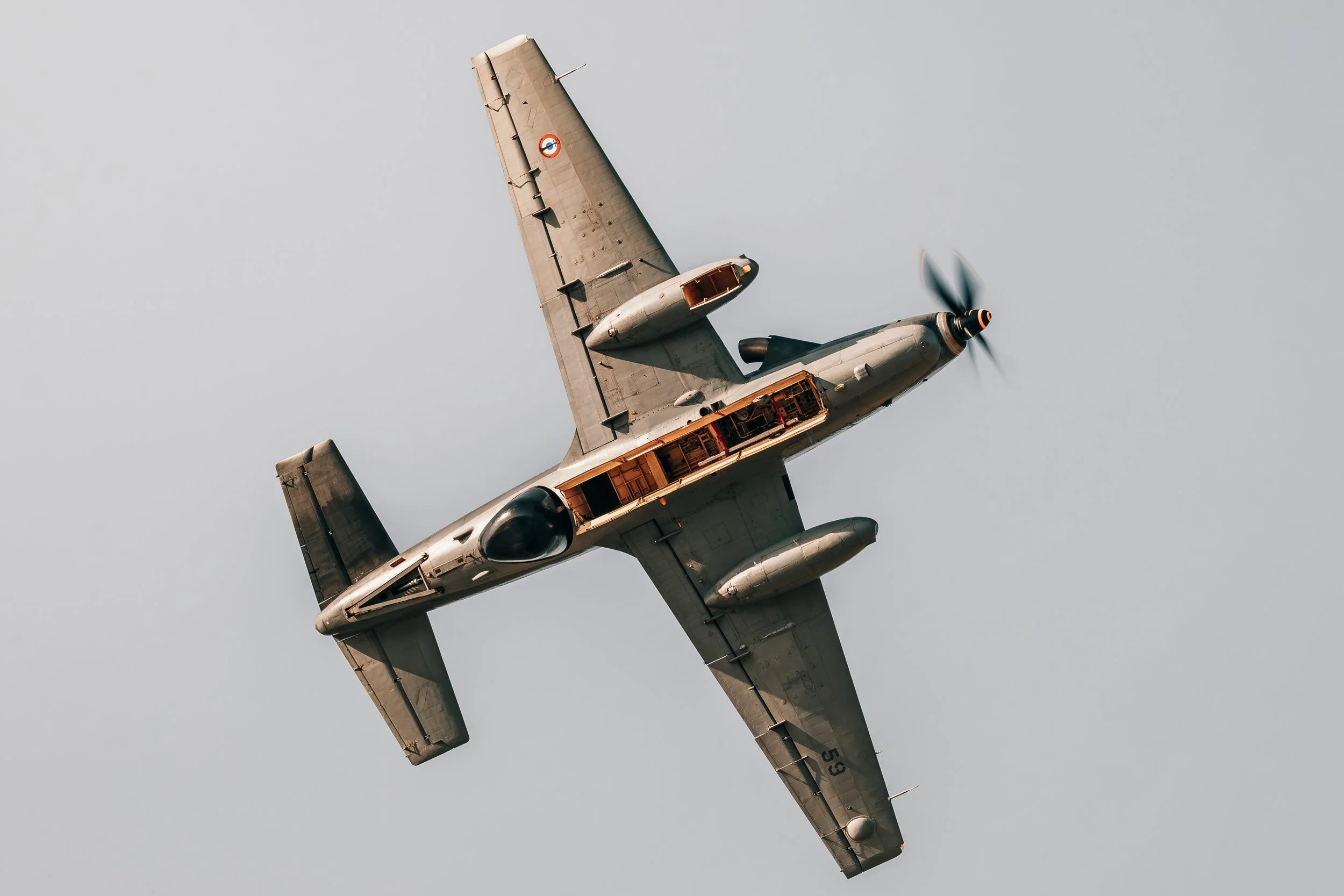 Un avion militaire de couleur grise en vol inclin 9 vers la gauche dans un ciel d E9nu E9ment neutre.