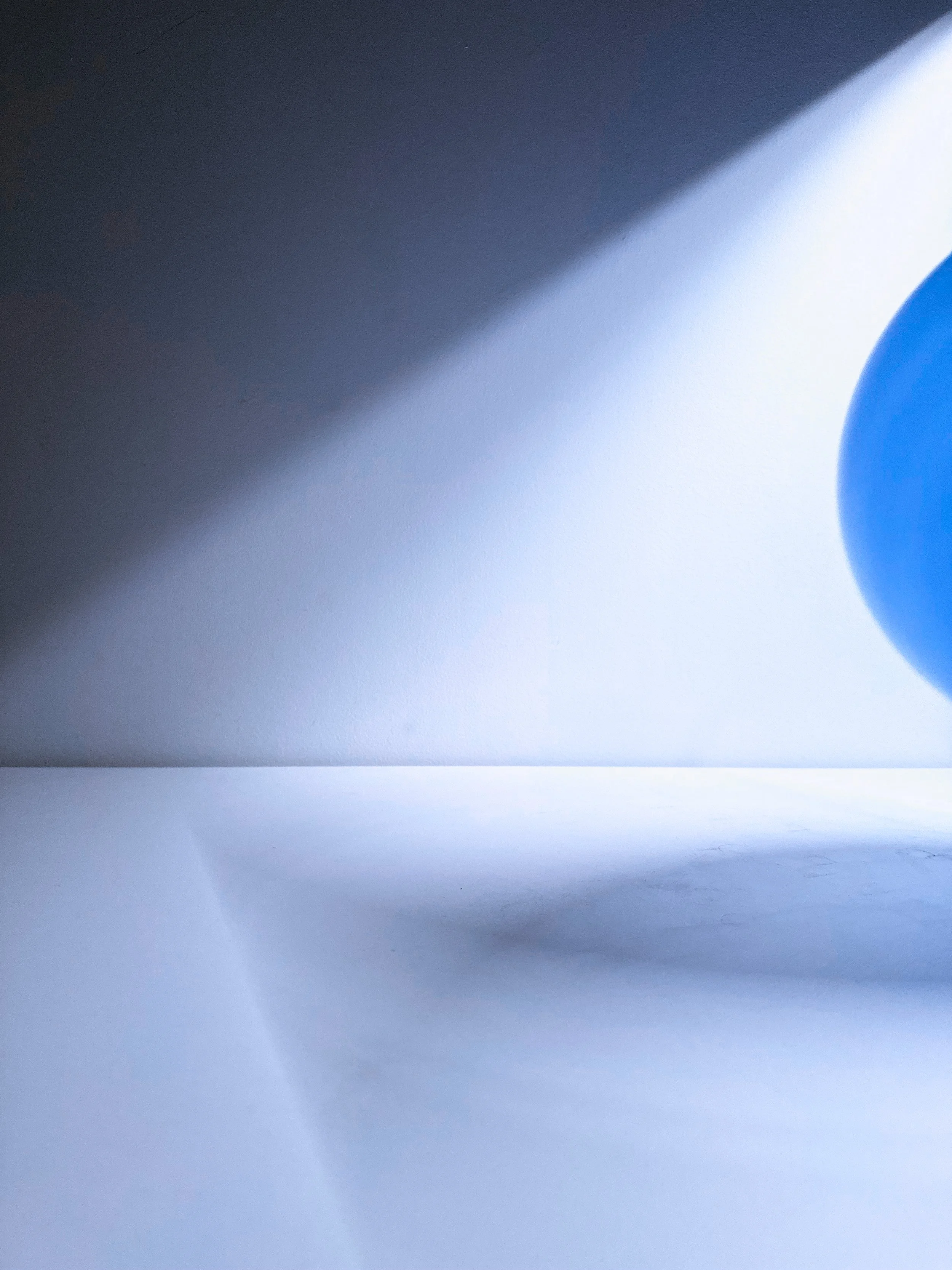 Close-up of a white surface with shadows, a light blue part, and a dark area in the upper left corner.