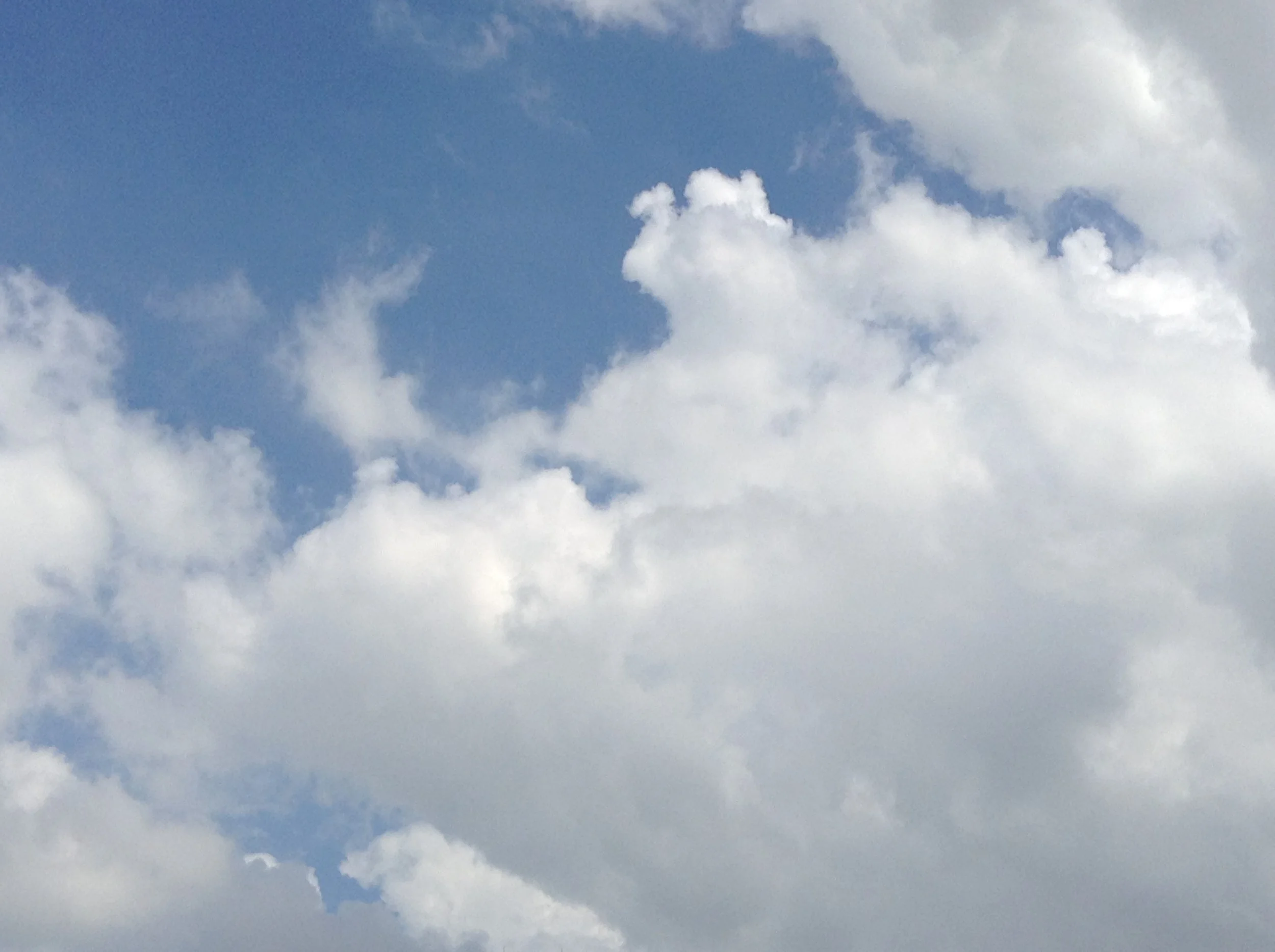 A partly cloudy sky with several white clouds and a blue background.