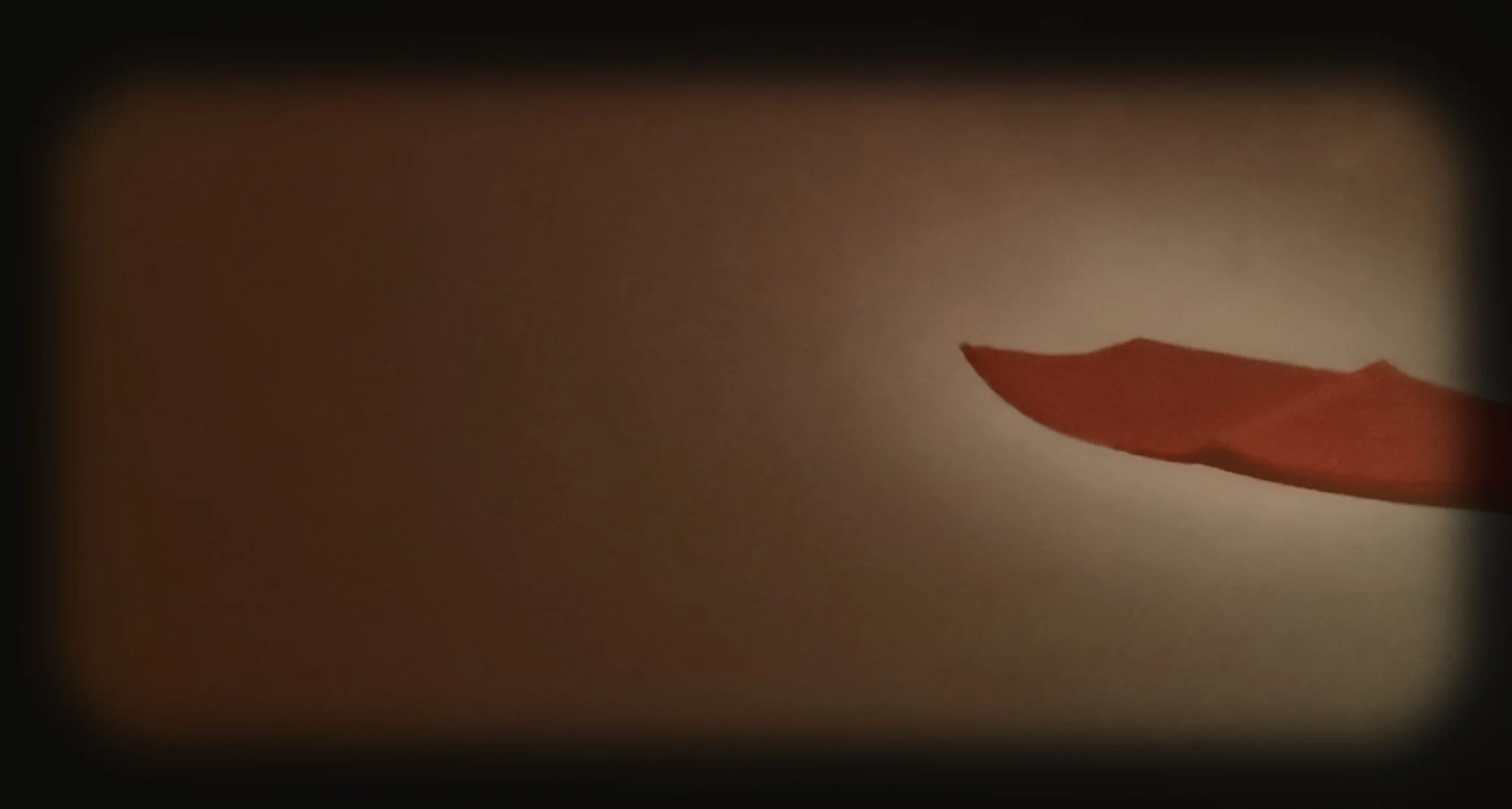 Close-up of a partially peeled red chili pepper against a beige background.