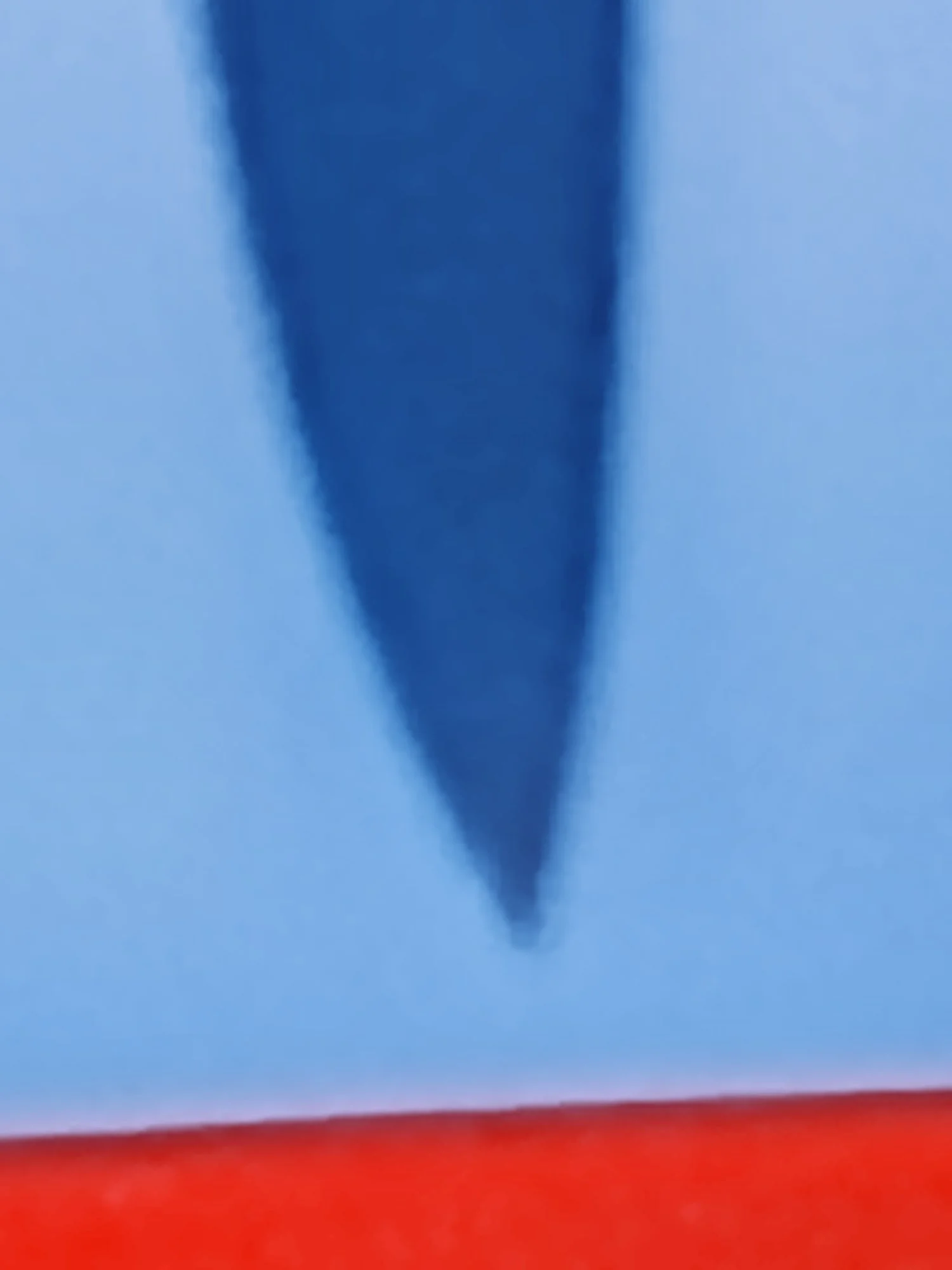 Close-up of the tip of an American paper airplane flying against a blue sky with a red horizon.
