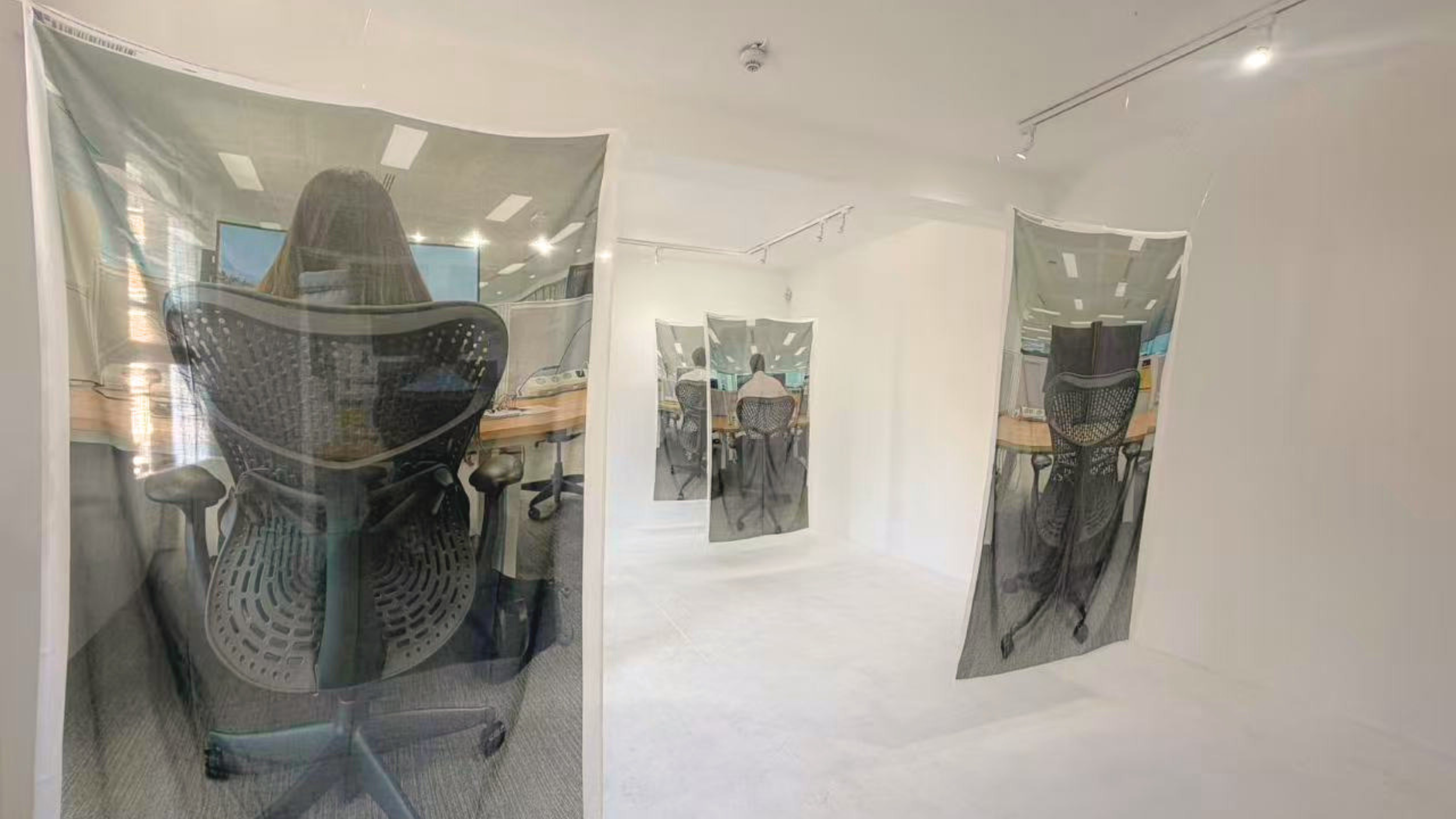 Office space with glass partitions featuring images of people working at desks.