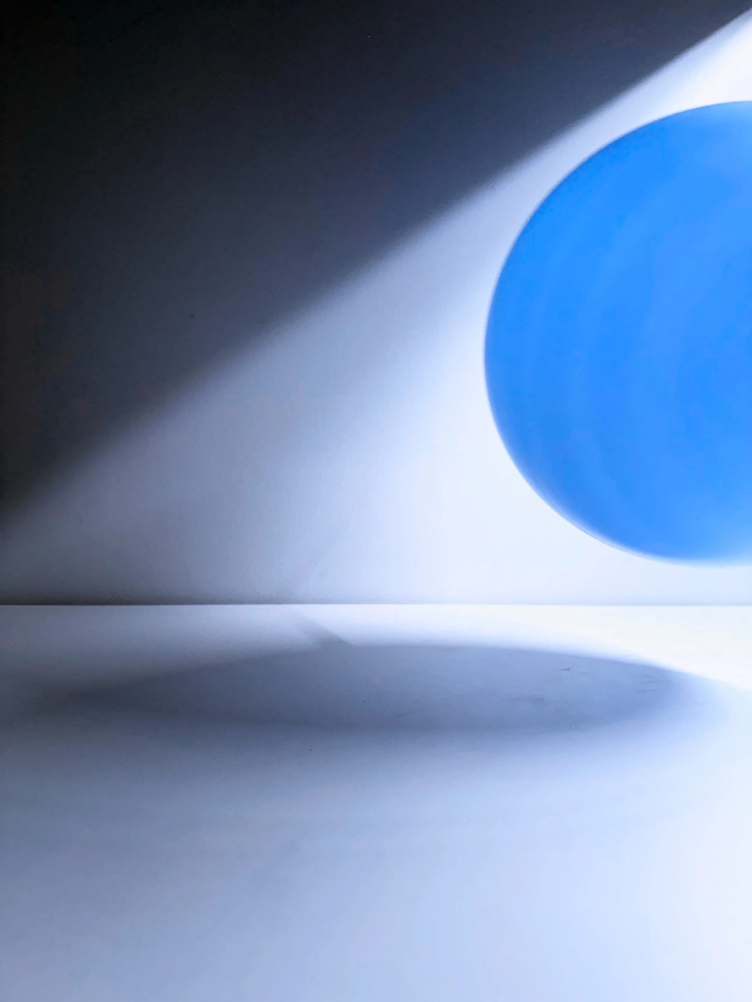 Close-up of a blue button on a computer keyboard, with light and shadows cast around it.