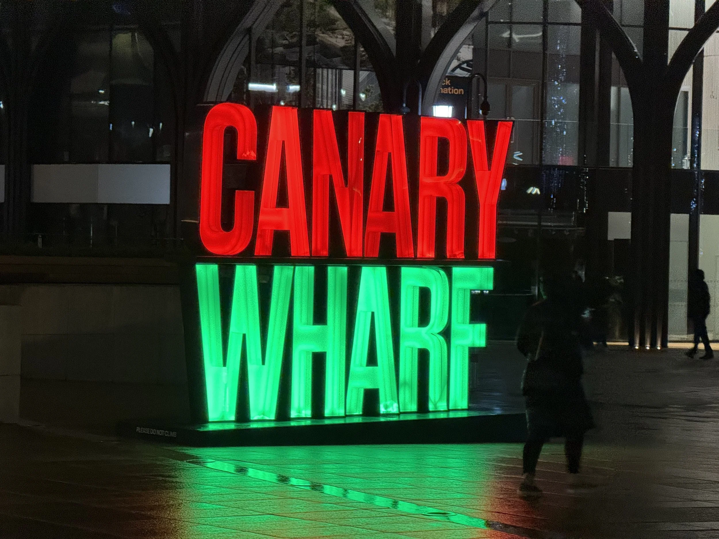 A brightly lit sign with the word 'CANNABY' in red neon letters, and below it, the word 'WEED' in green neon letters, reflected on the floor.