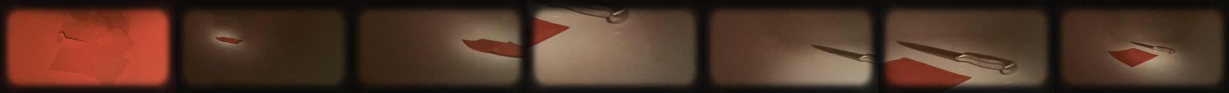 Close-up of a glass ink or paint bottle with a metallic squeeze nozzle, and a red card underneath.