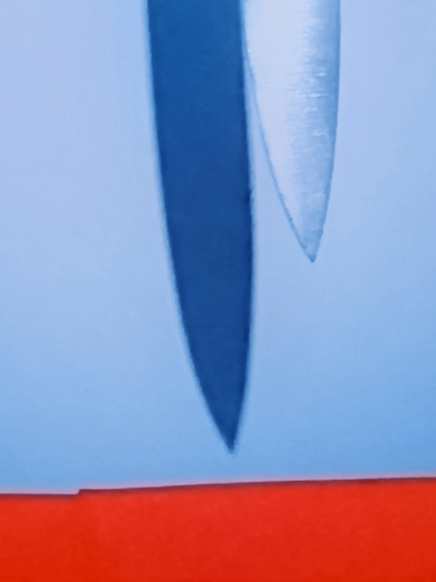 Close-up of a paper airplane with a blue sky in the background, the photograph is inverted.