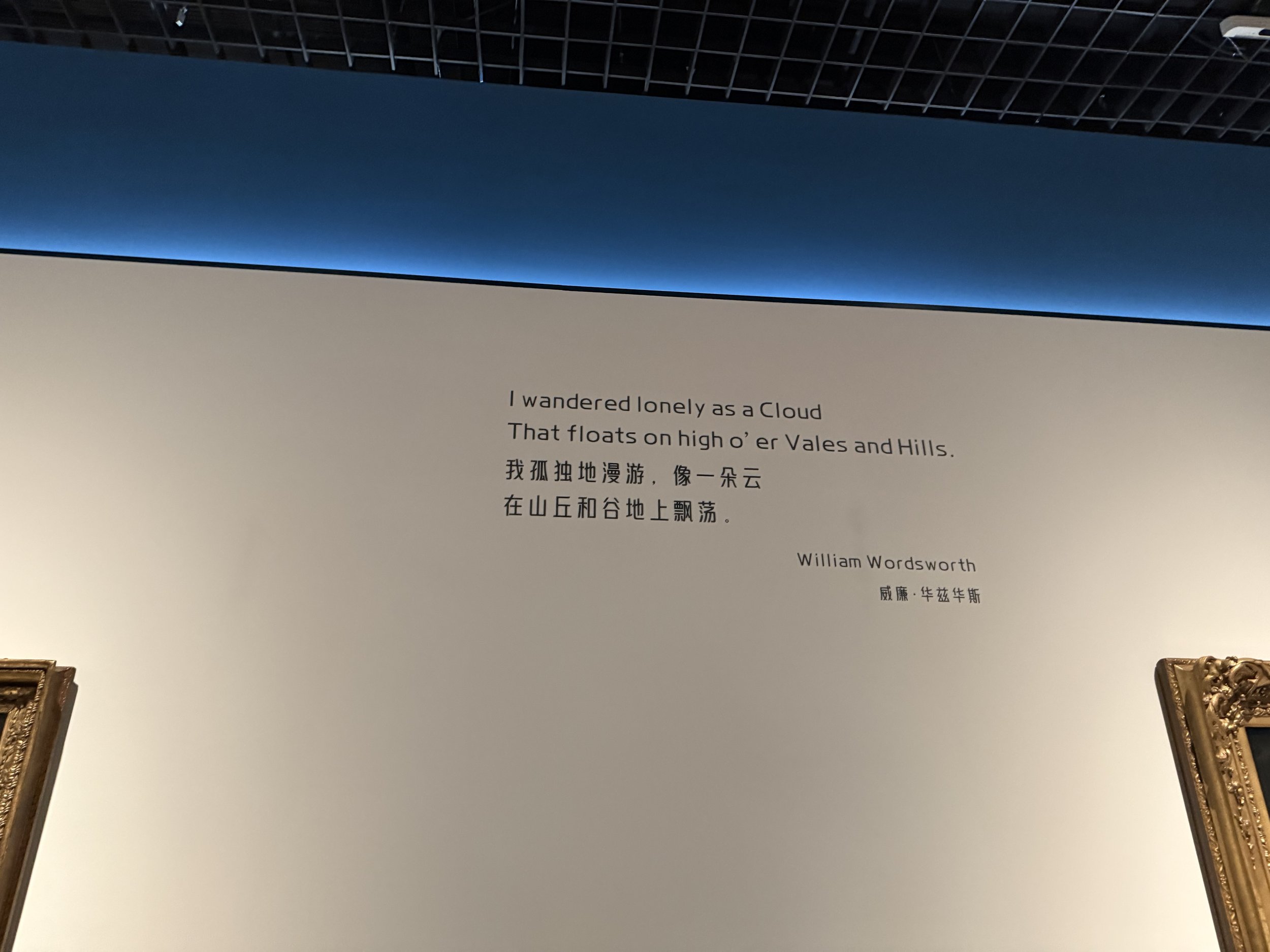 Museum wall with poetry quote by William Wordsworth in English and Chinese, partially visible, and ornate picture frames at the bottom corners.