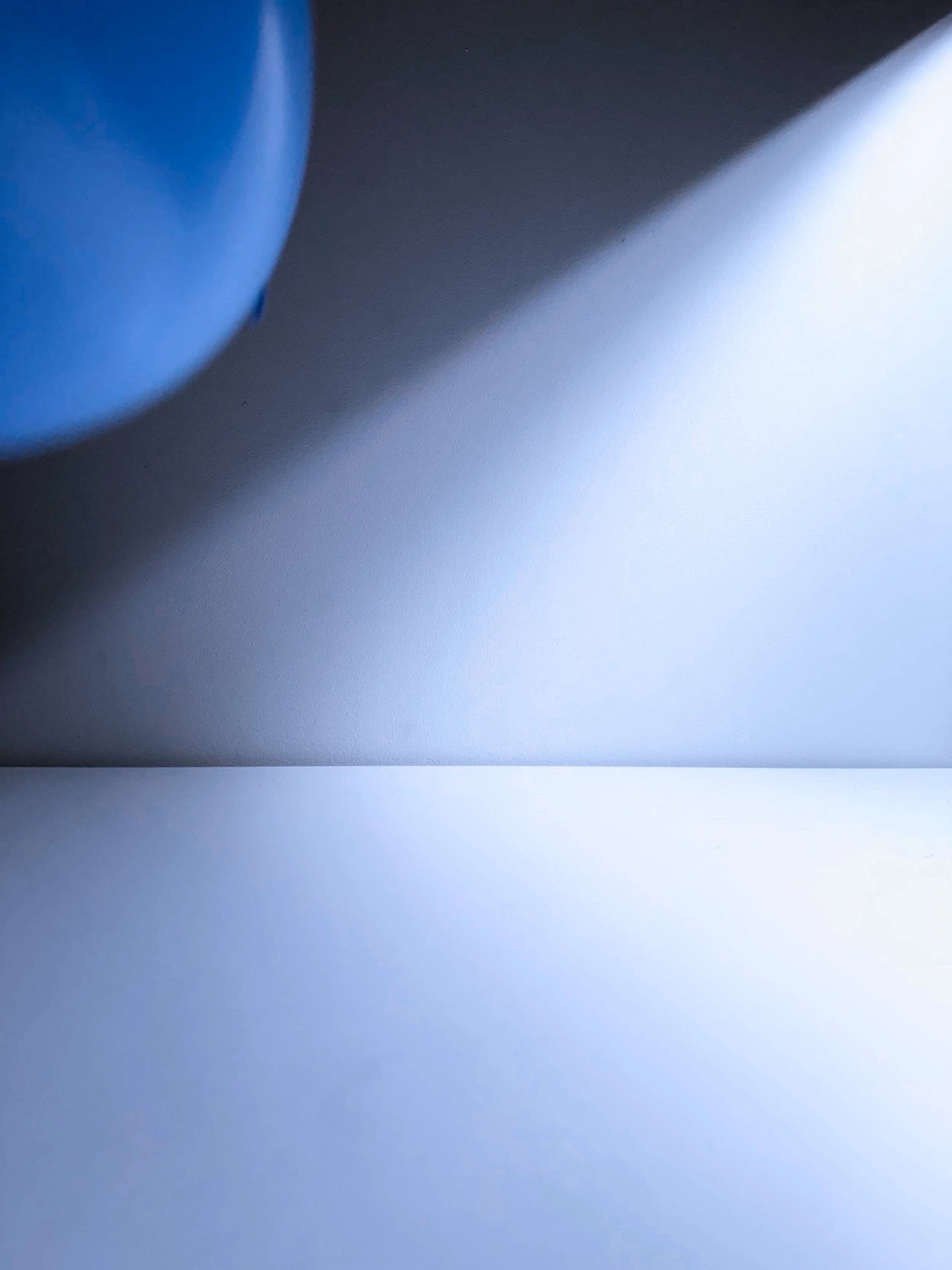 Close-up of a blue object on a gray surface with a shadow cast on the right side.