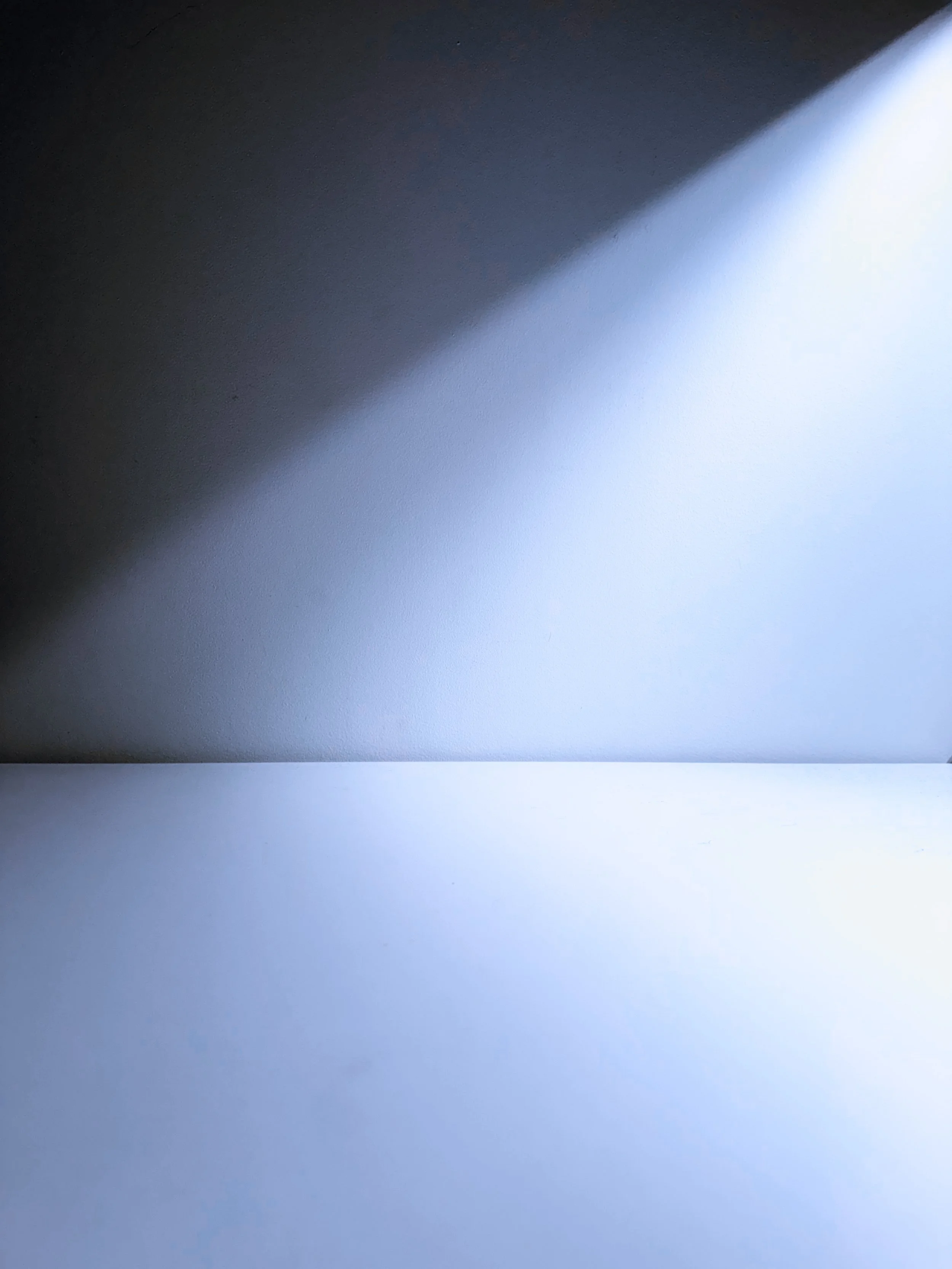 Abstract image with a diagonal shadow dividing dark and light areas, no discernible objects or specific features.