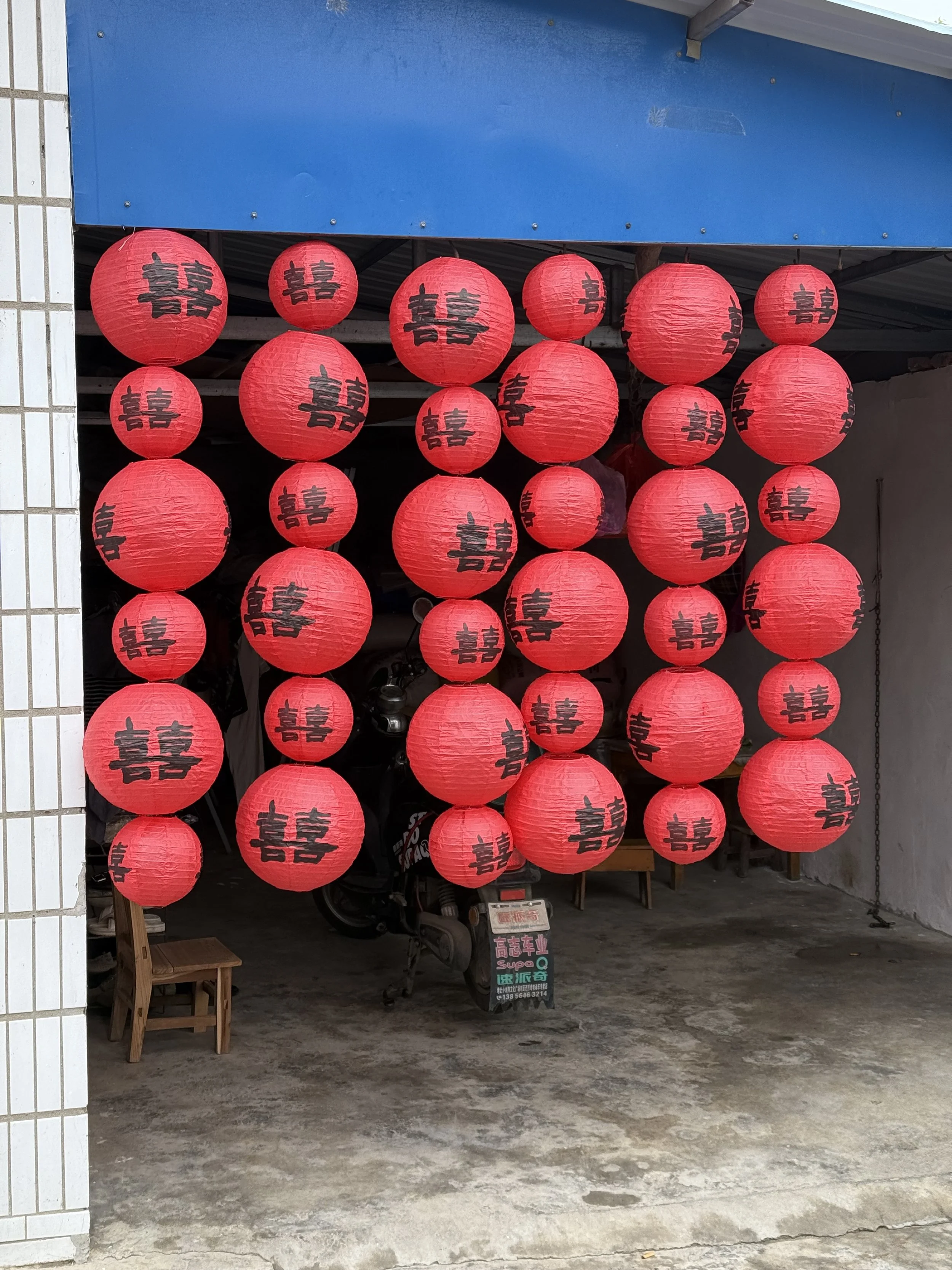 A display of red paper lanterns with black Chinese characters hanging in front of a building entrance. The lanterns are arranged in multiple rows, creating a festive look.