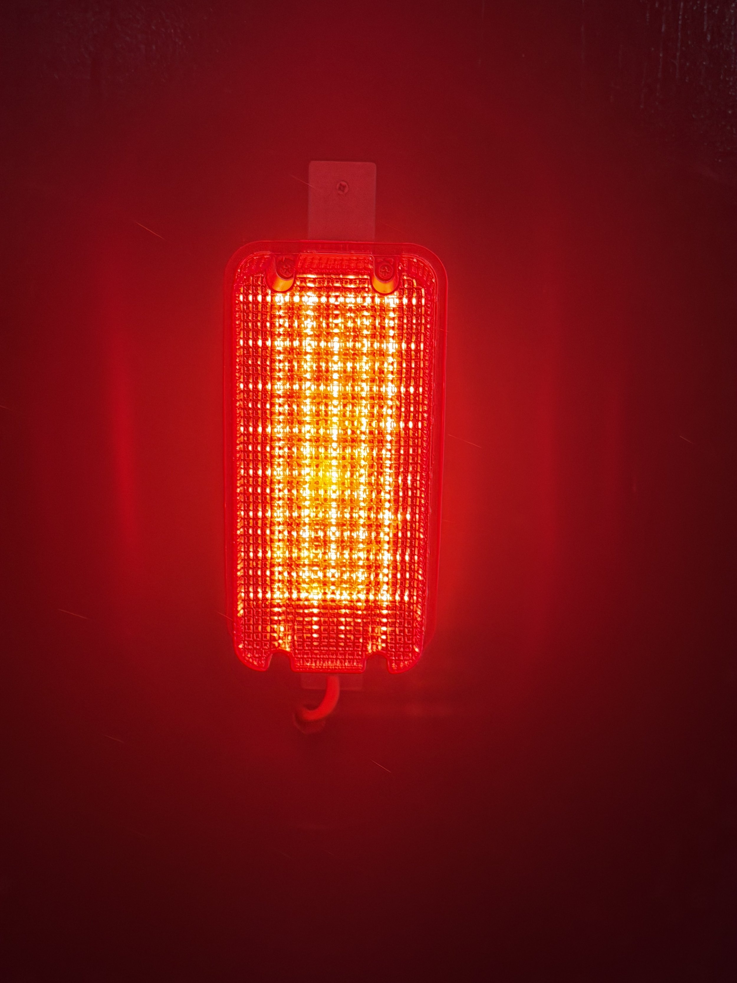 A bright red LED light on a dark surface, likely a warning or indicator light.