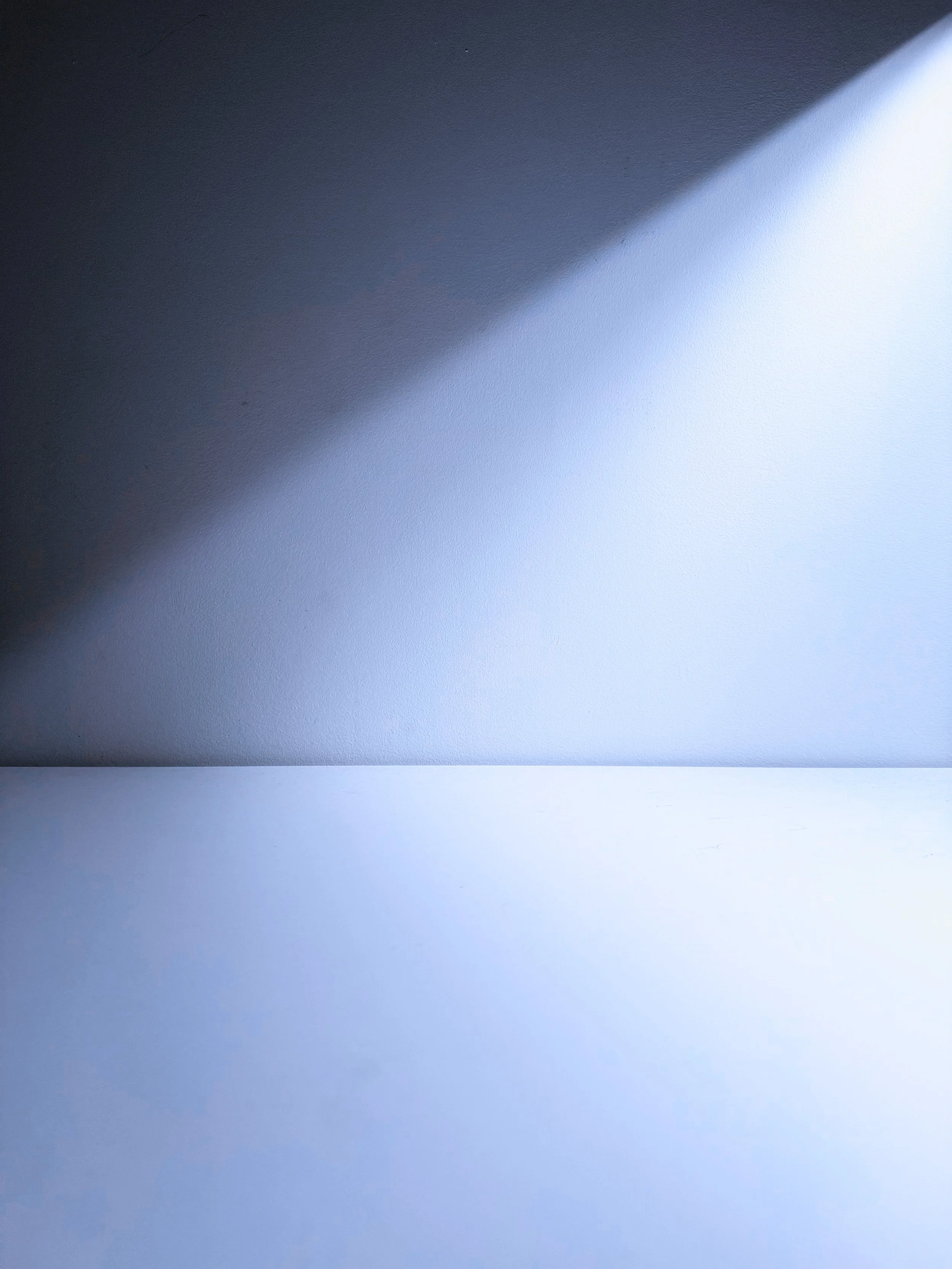 Close-up of a wall with a transition from a dark to a light area, creating a diagonal contrast.
