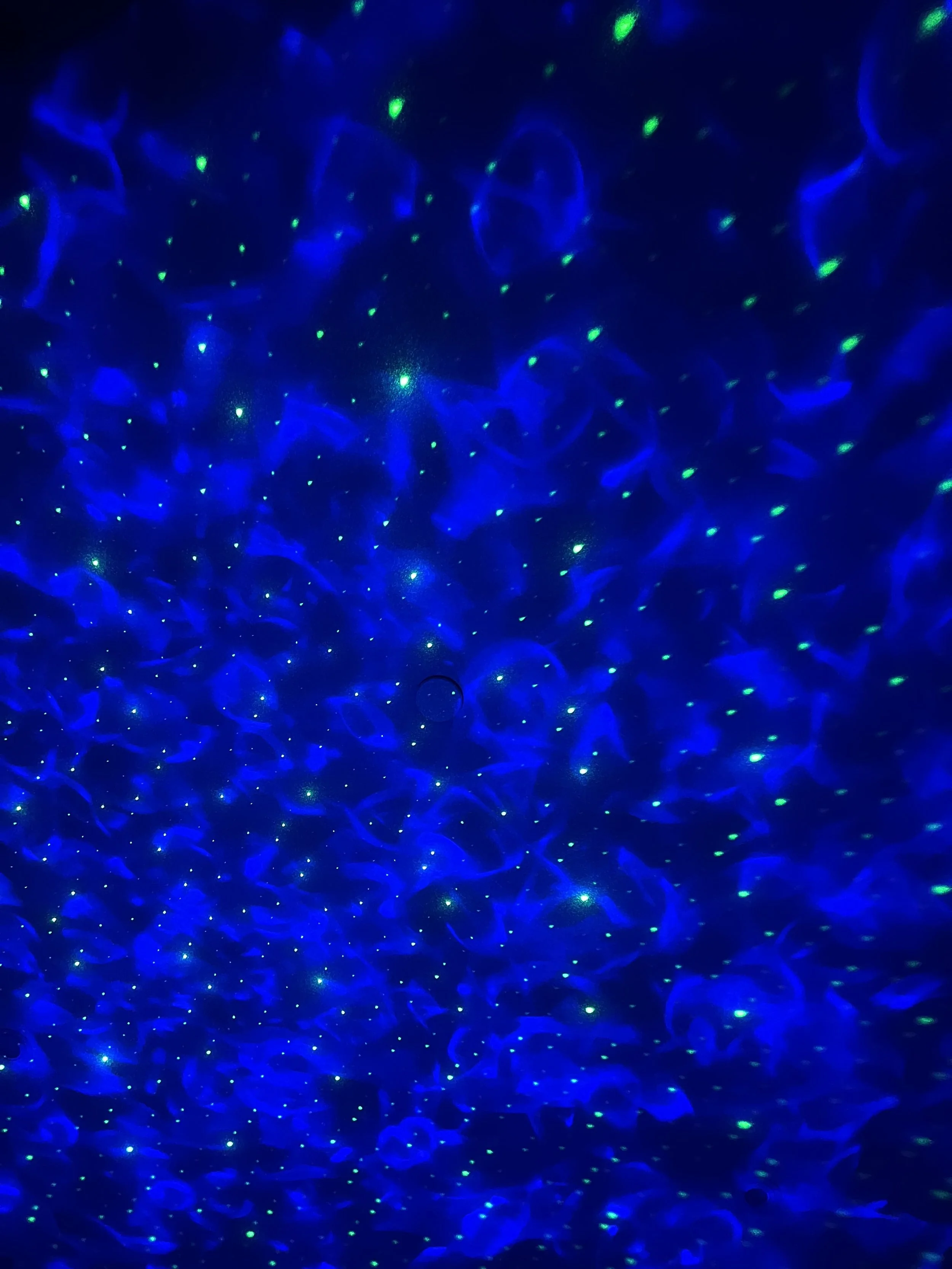 Dark background with blue and green light patterns resembling starry night sky or abstract light art.