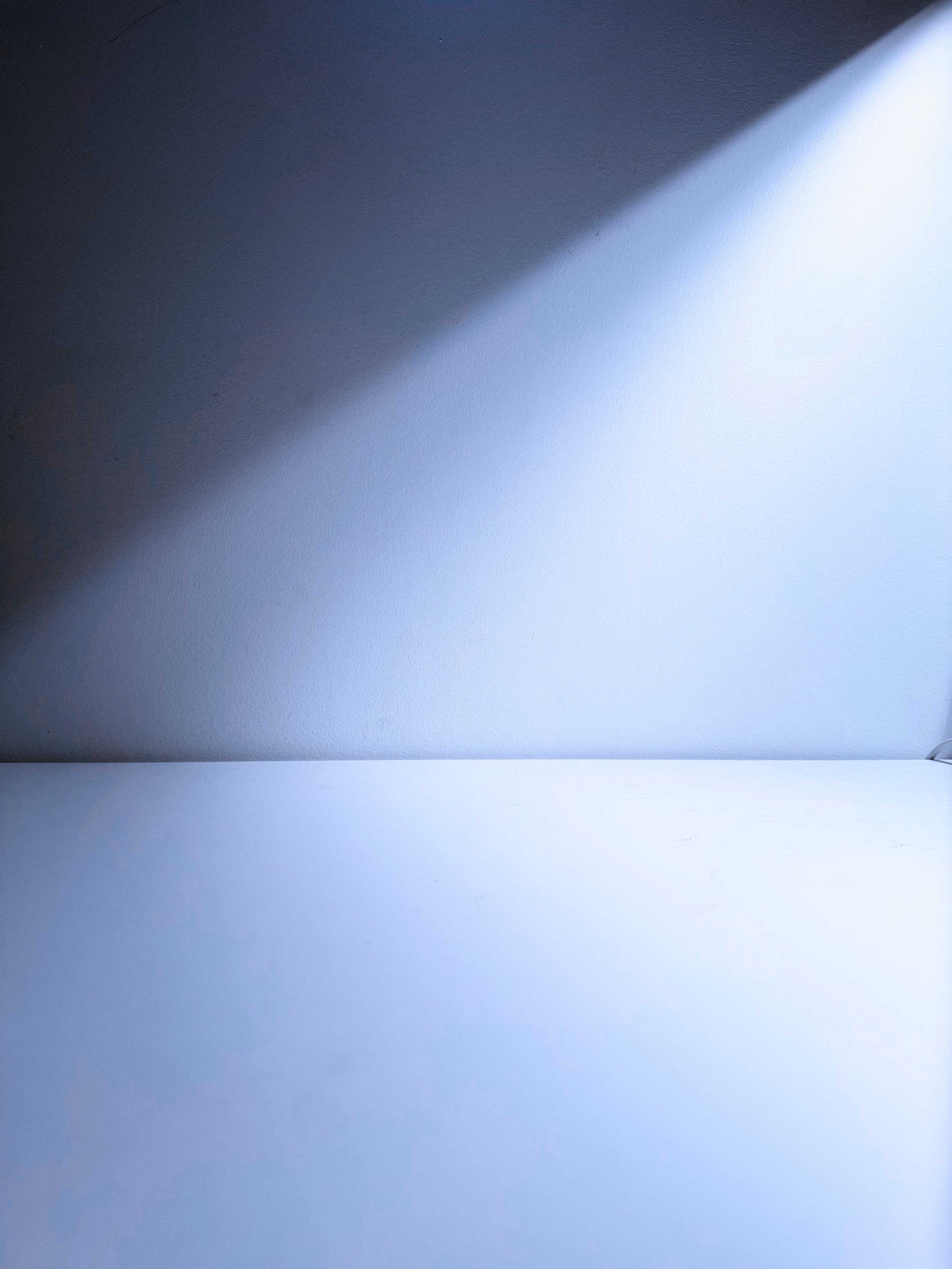 A blue and white wall with a diagonal shadow dividing the two colors.