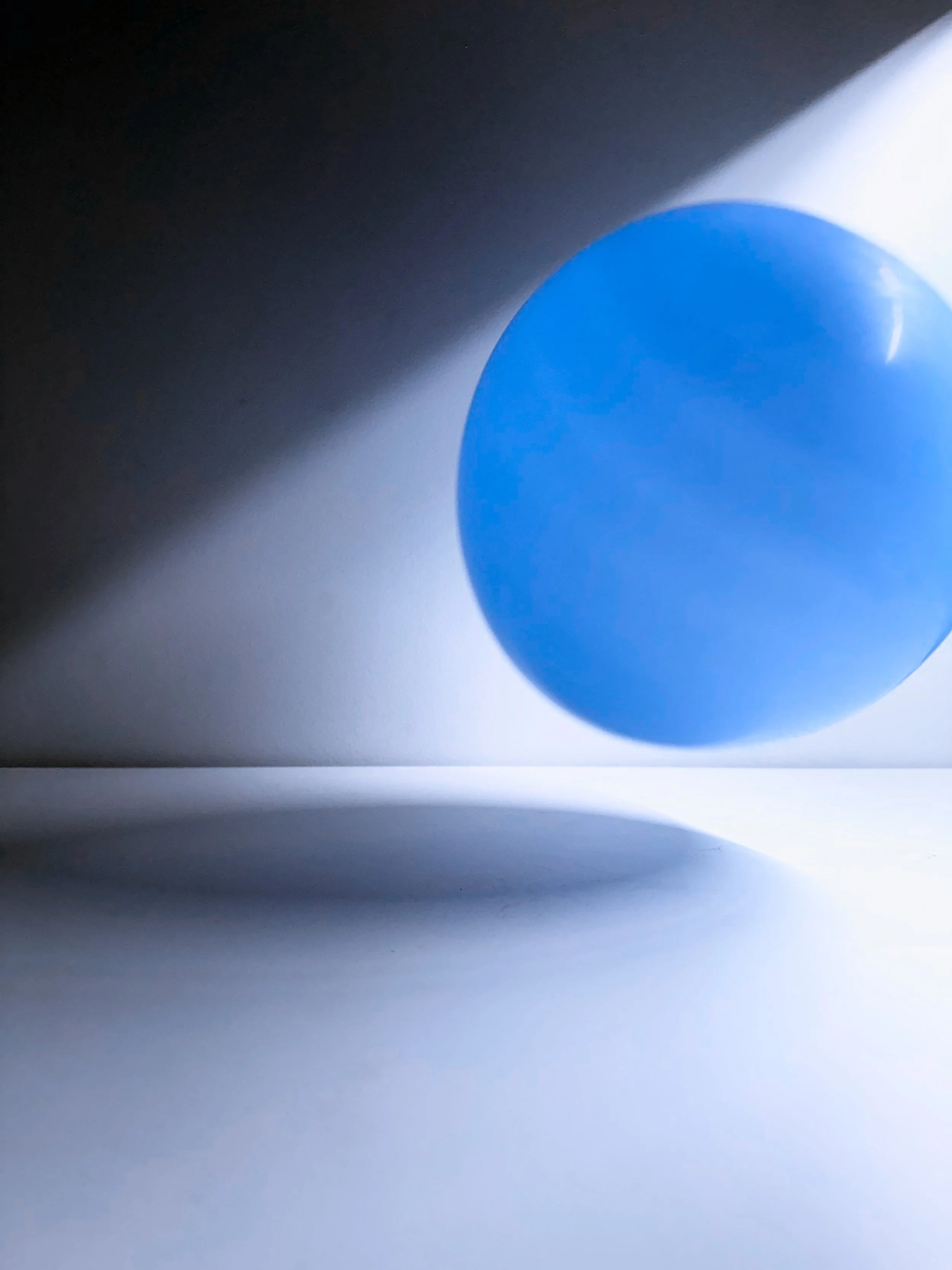 Close-up of a blue pill with a shadow cast on a white surface.