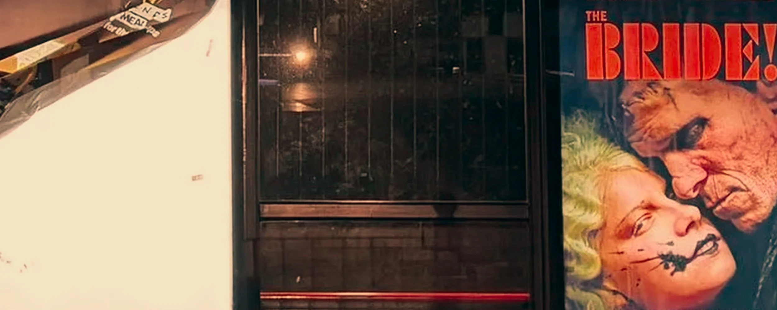 A glossy poster featuring a woman with blonde hair and a tiger, with the text 'The BReD' in bold red letters. The poster is on a dark wall, next to a black metal and glass shelf.