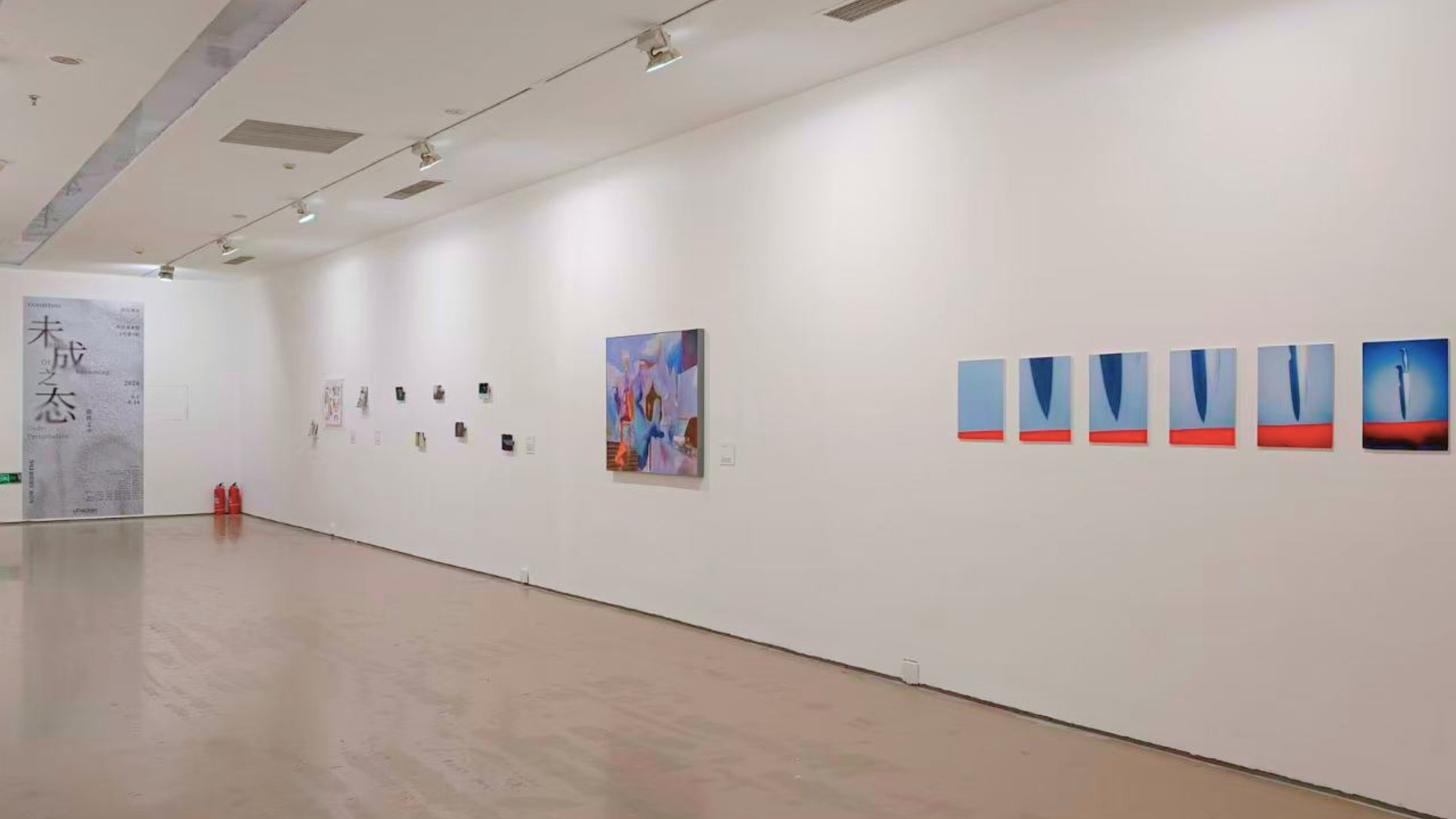 View of an art gallery with paintings and artwork displayed on white walls, including abstract and contemporary art pieces.
