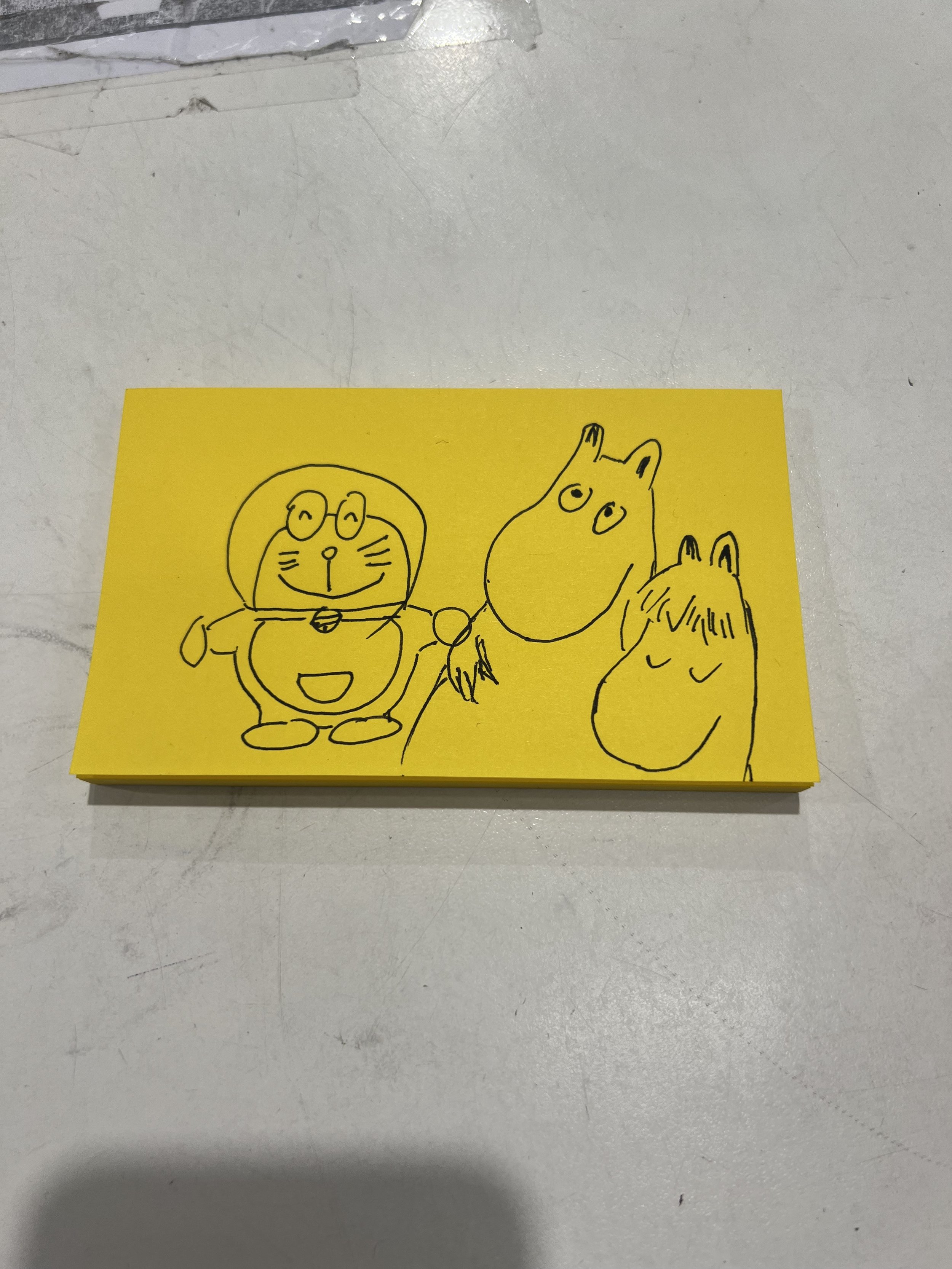 A yellow paper with a black line drawing of cartoon animals including a dog, a bear, and a rabbit, holding hands.