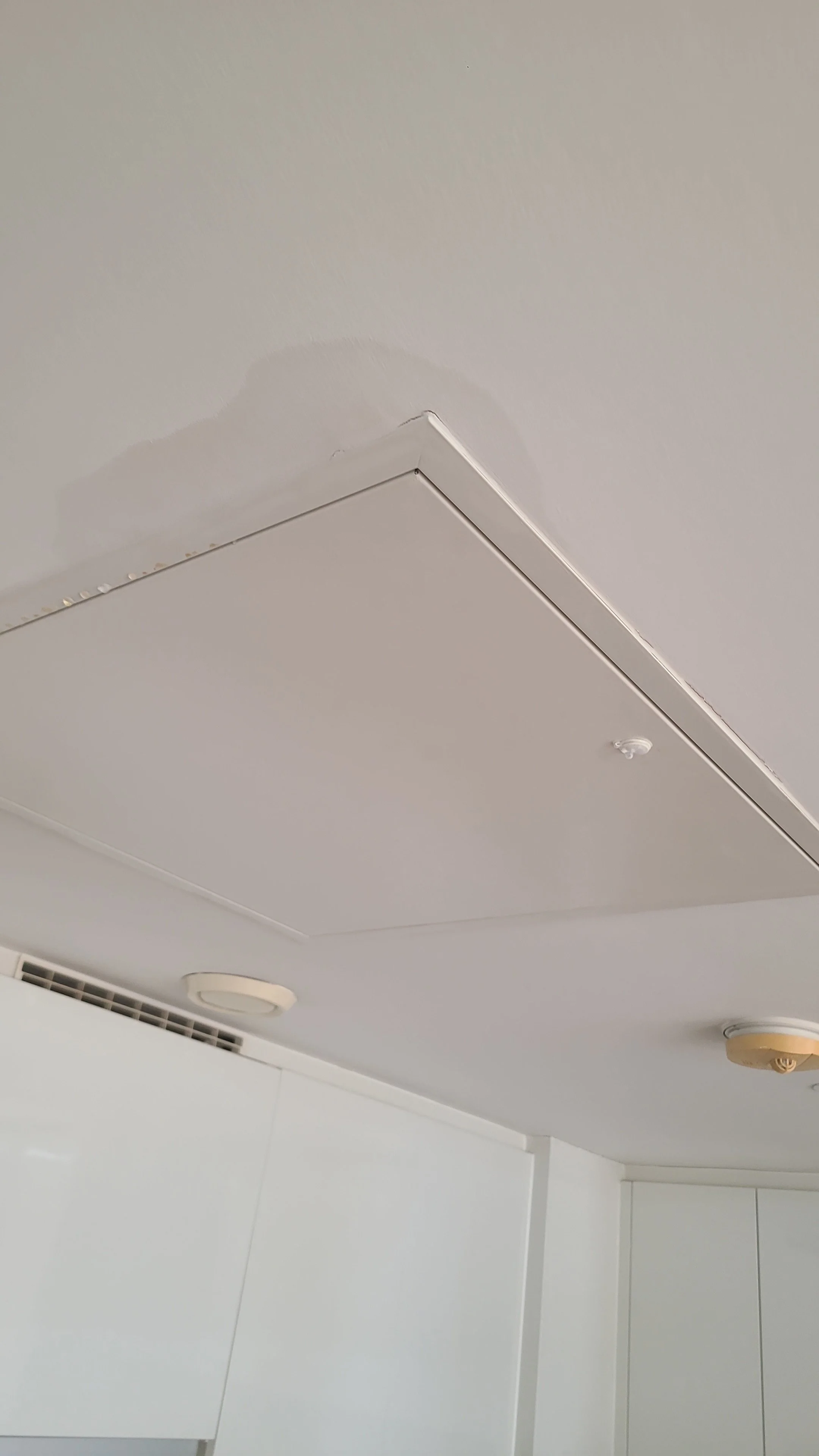 Ceiling with air vents, smoke detector, and light fixtures in a building.