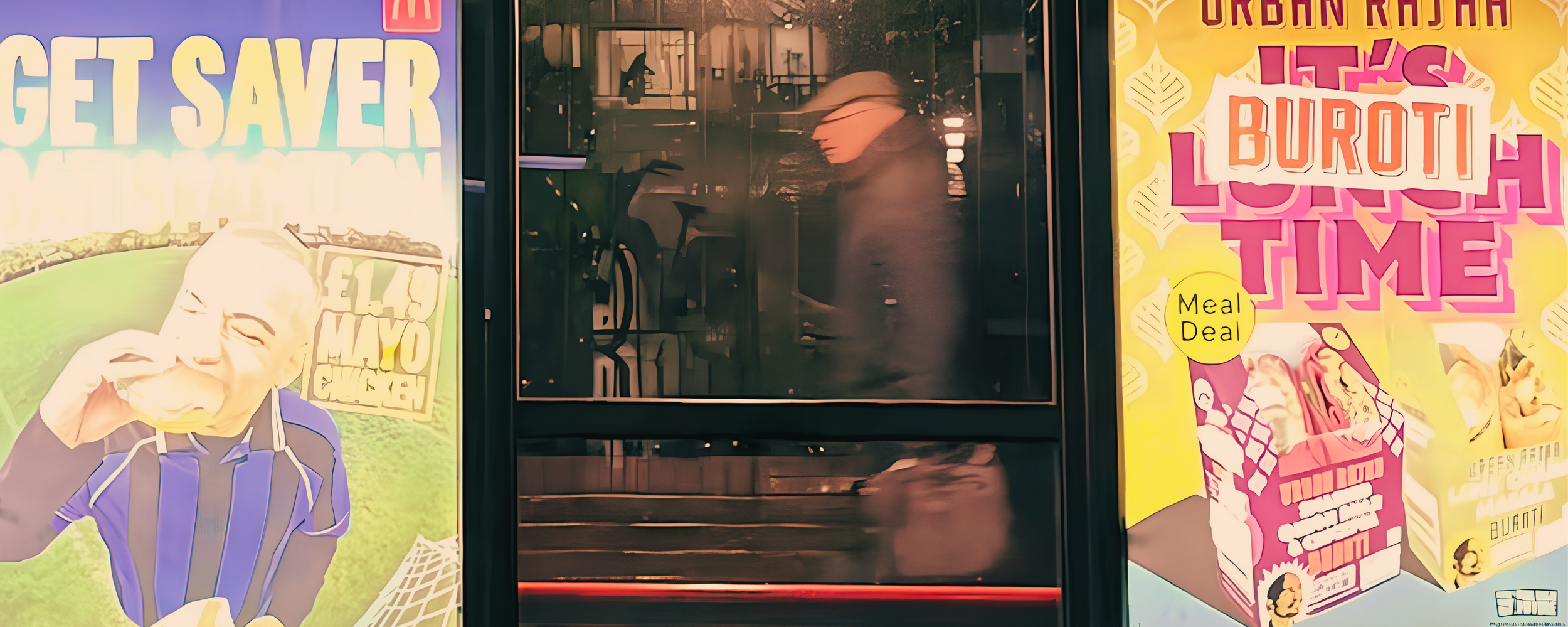 Glass storefront with colorful posters on either side advertising a meal deal and food items. The posters feature illustrations of people eating and shopping, with large, bold text promoting savings and meal deals.
