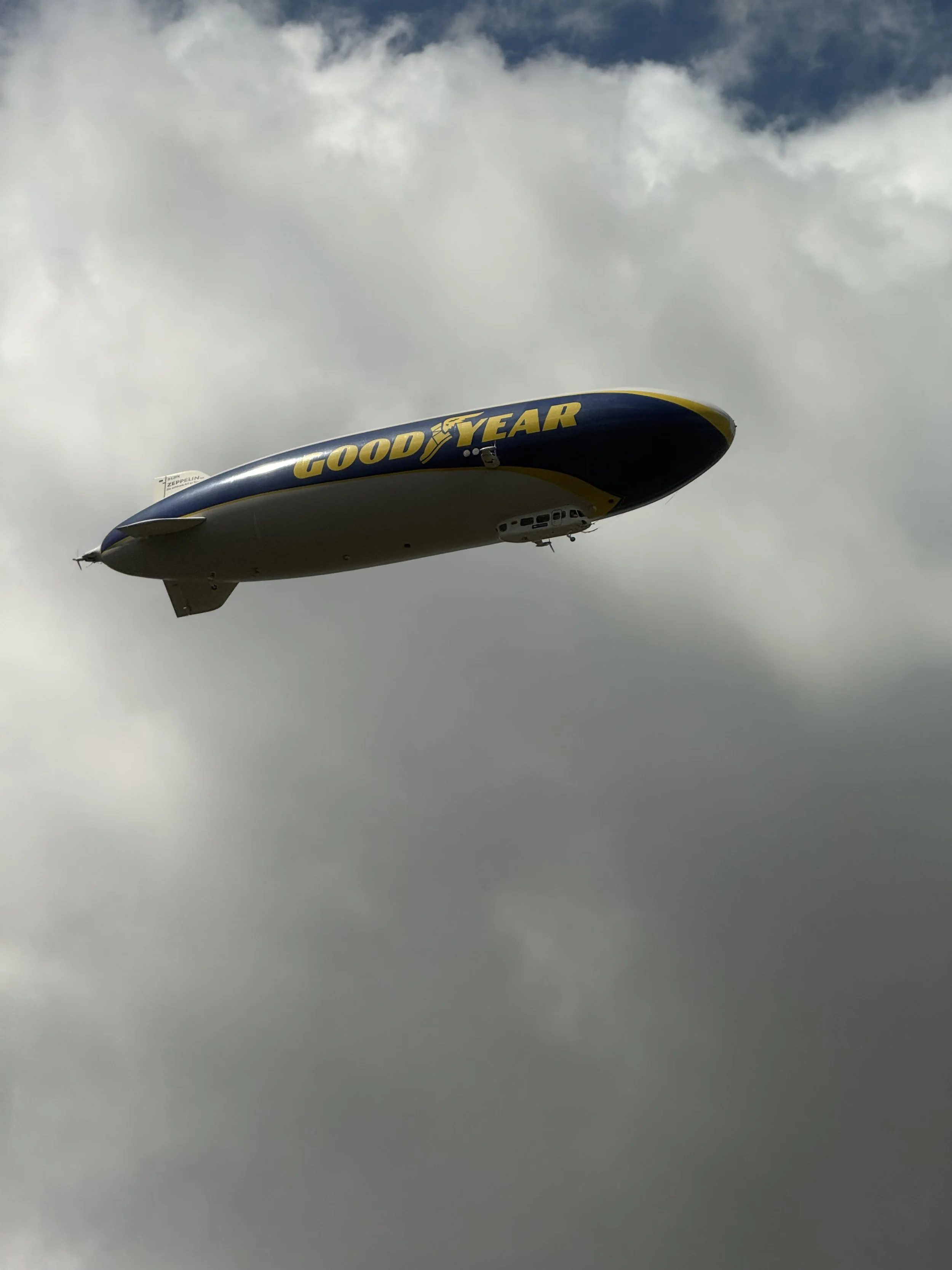 A blimp or airship with 'Goodyear' written on the side flying in the sky, surrounded by clouds.