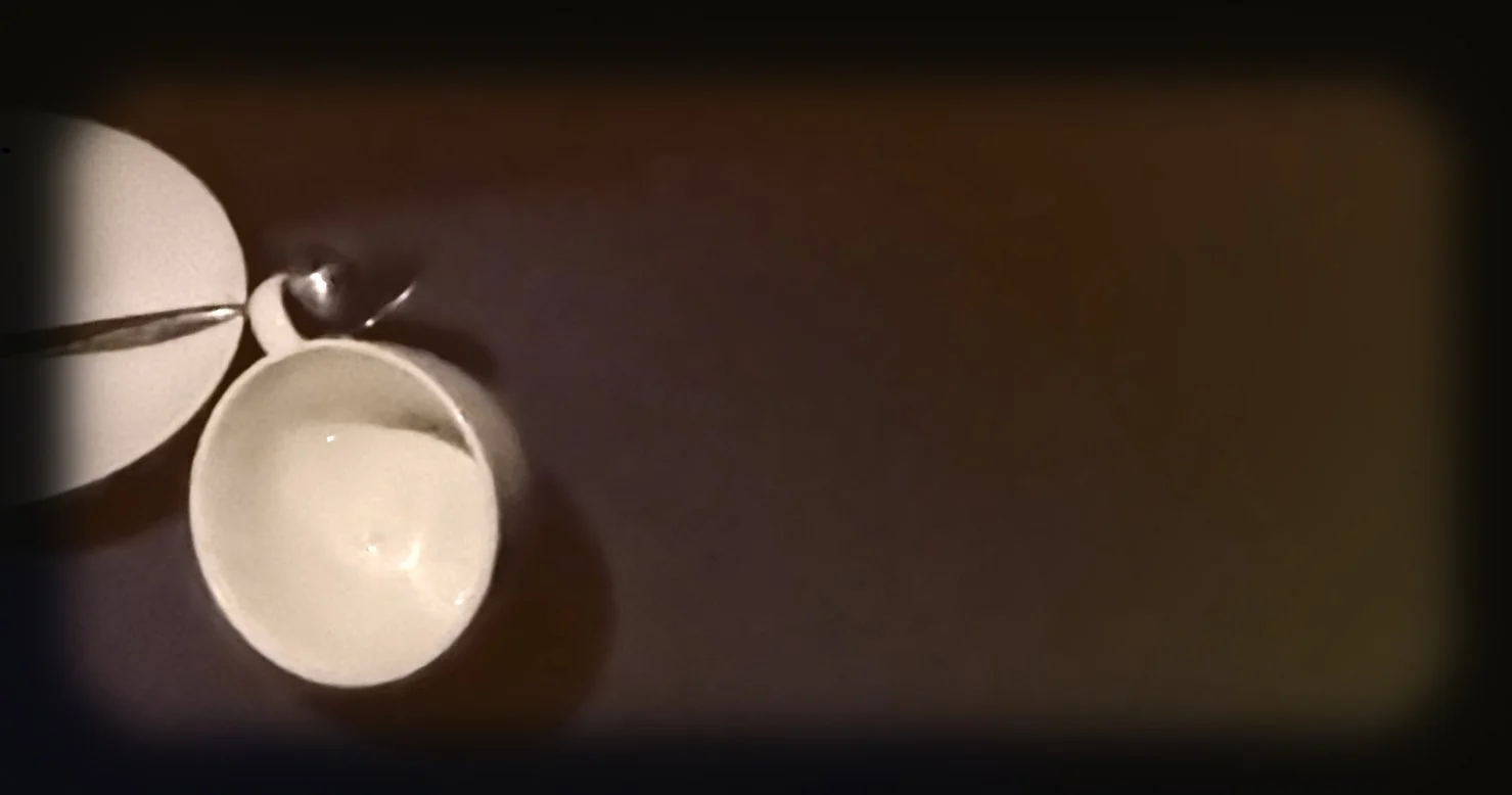 Close-up of a spoon pouring from a small bowl into a larger bowl on a dark surface.