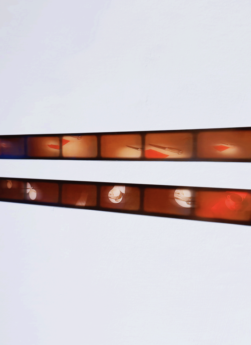 Close-up of two parallel strip lights with reddish-orange and white glowing bulbs against a plain, light-colored background.