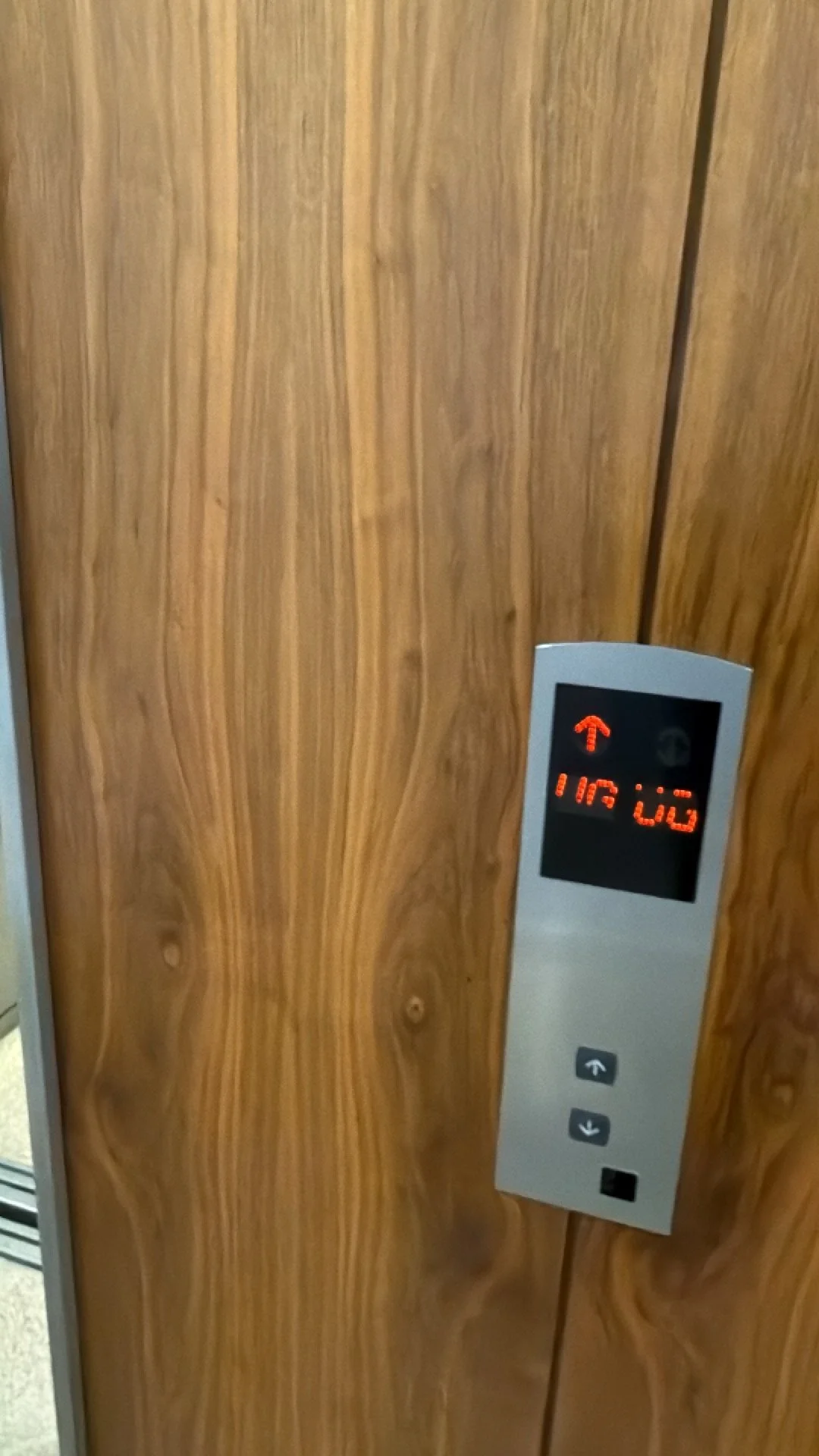 The photo shows an elevator control panel on a wooden wall, with an illuminated display showing floor number 11 and the floor button for 11.