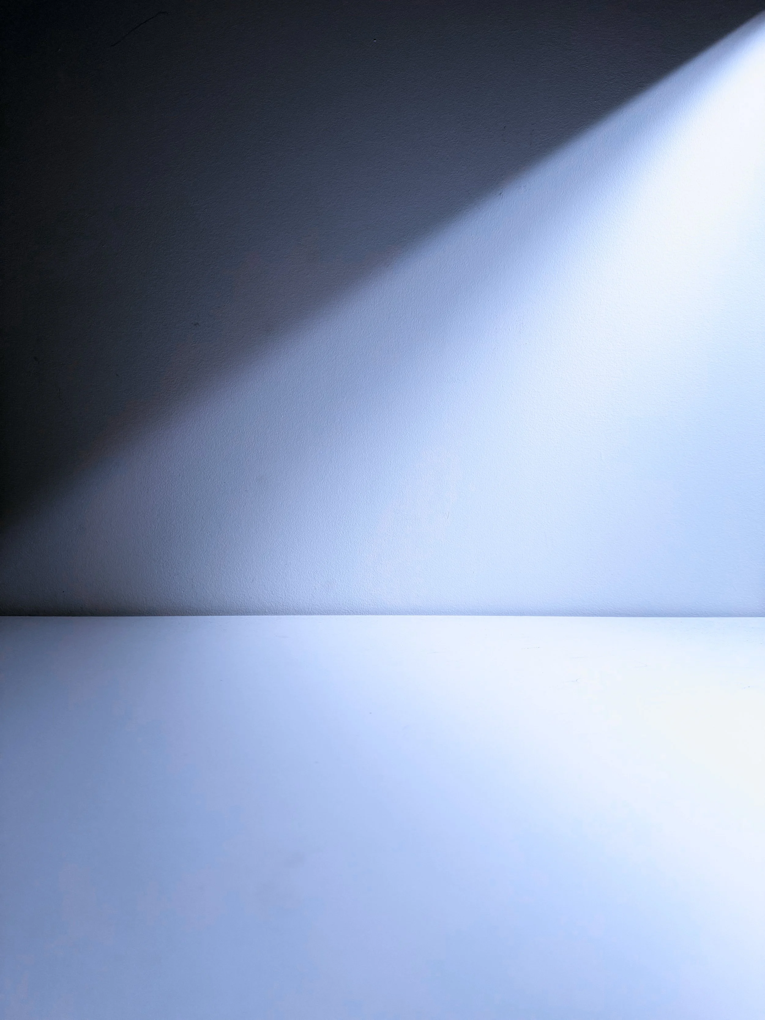 Close-up of a wall with light and shadow creating a diagonal line across the surface.