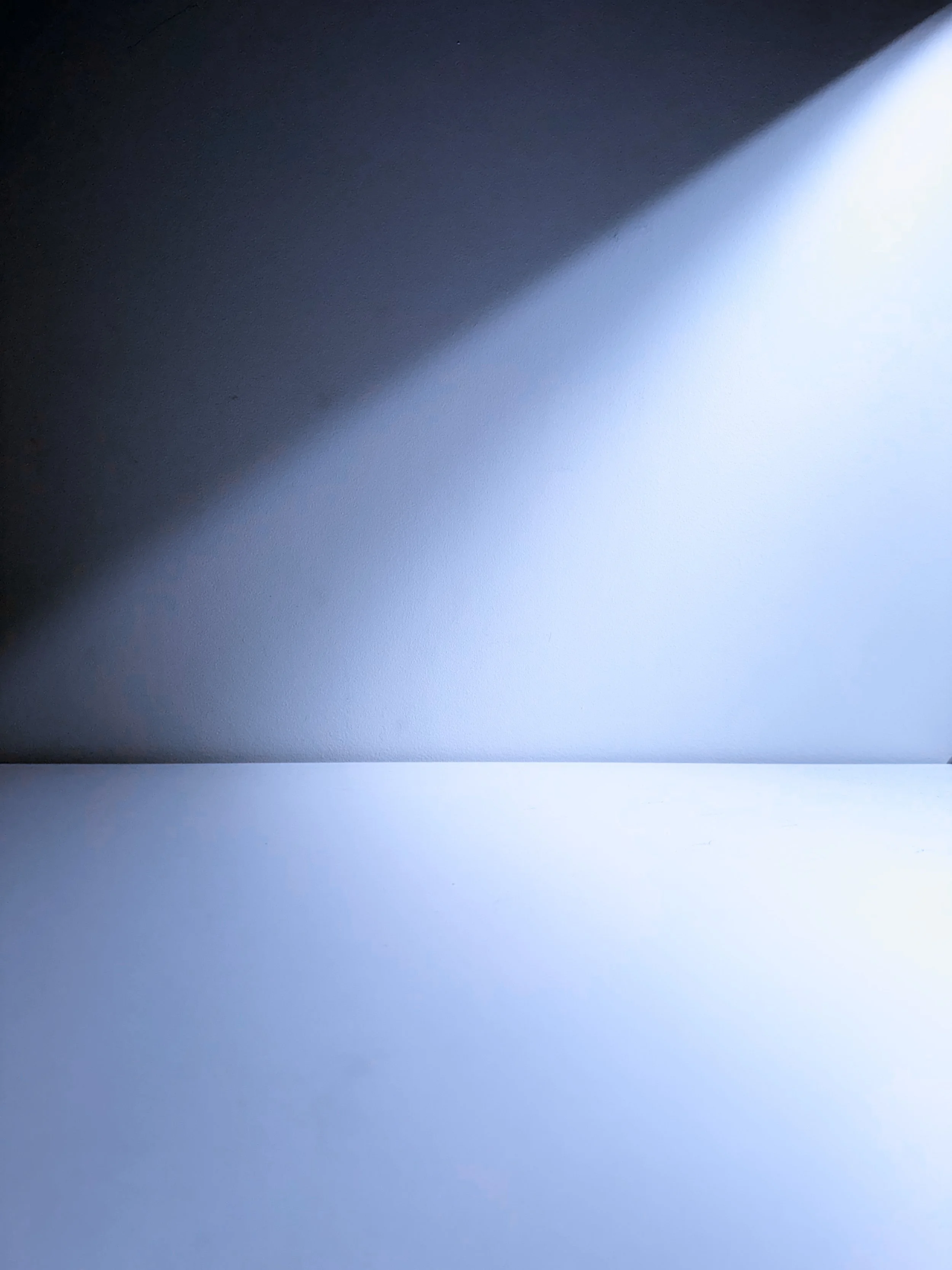 Close-up of a computer screen showing a mostly white and light gray surface with a shadow cast across it, possibly the edge of a monitor or a sheet of paper with a shadow.