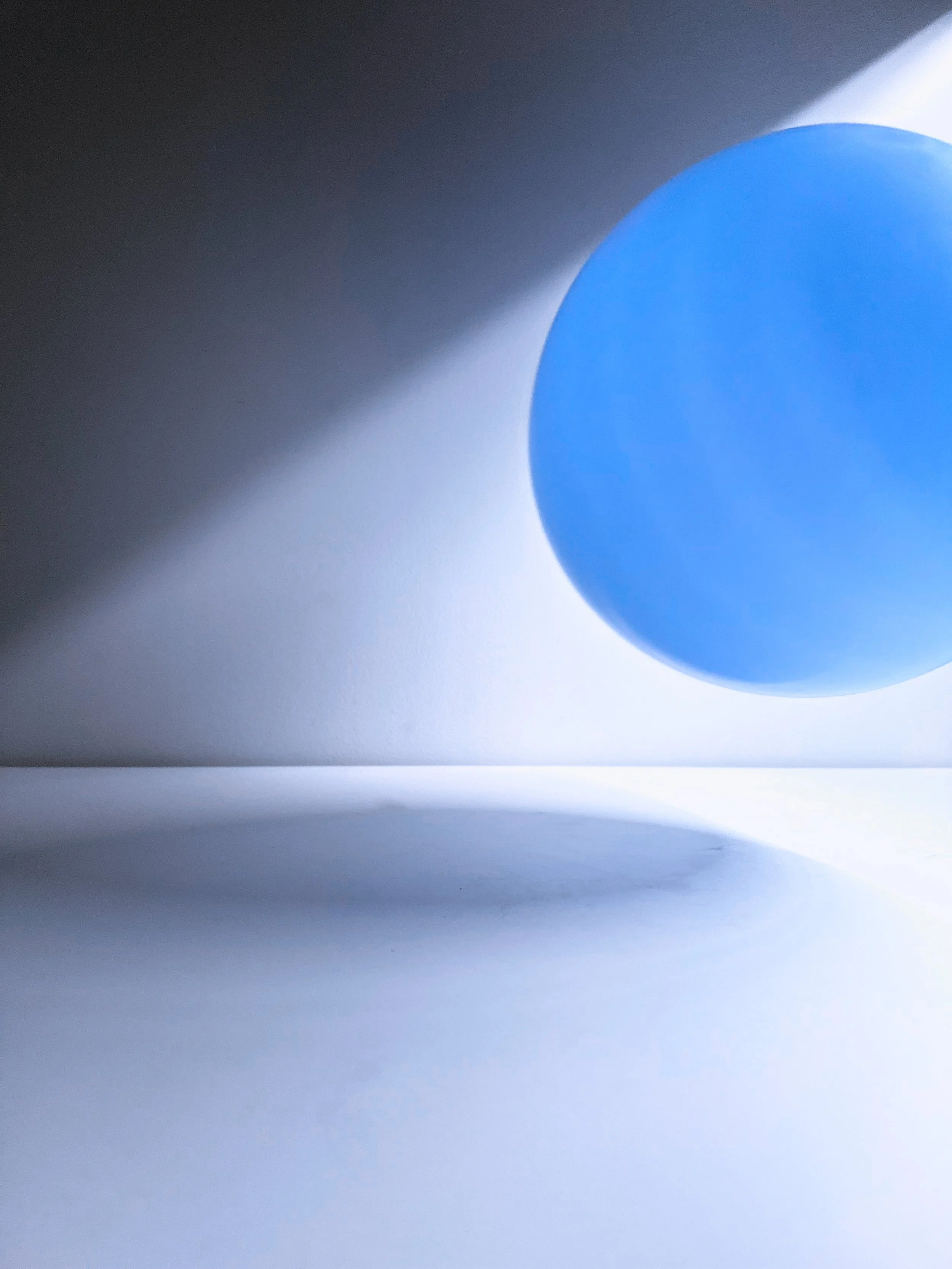 Close-up of a blue pill casting a shadow on a white surface with a gradient background.