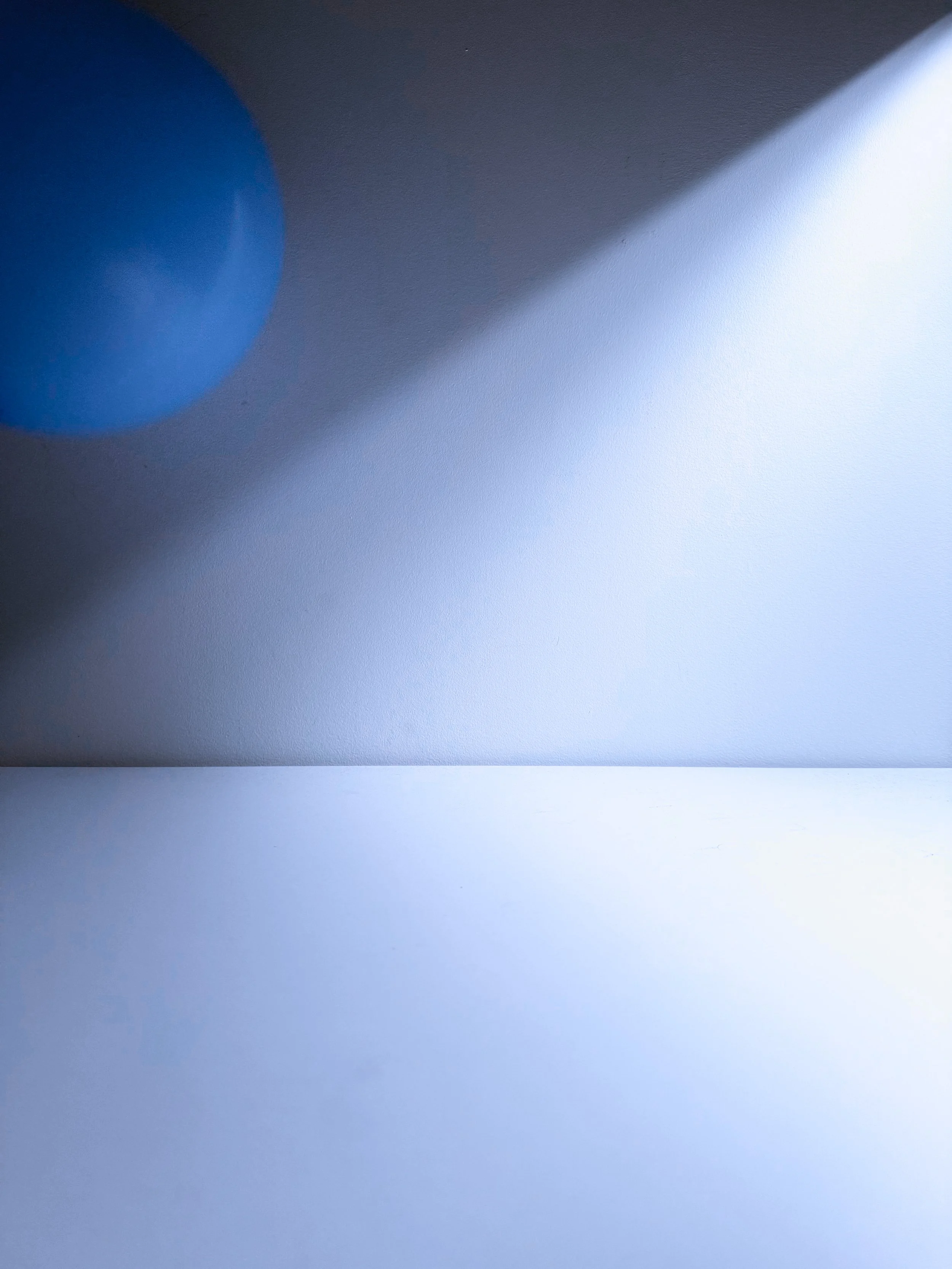 Close-up of blue and white circular objects on a textured surface, with blue and white shadows and a gradient of light.