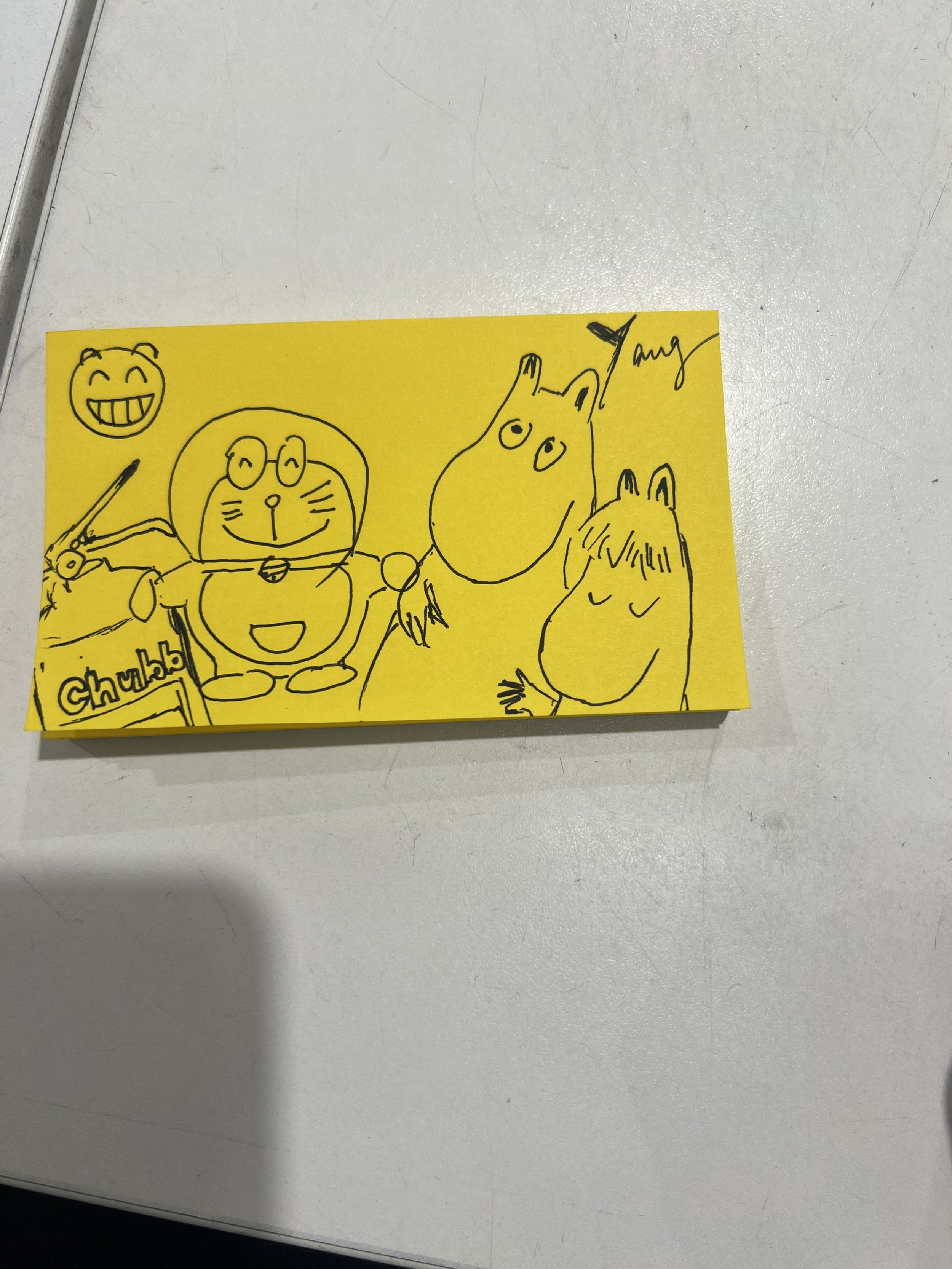 Hand-drawn sketch of various cartoon characters on a yellow sticky note, including a smiling bear, a character with glasses, and a character with a bun, all signed by Amy.