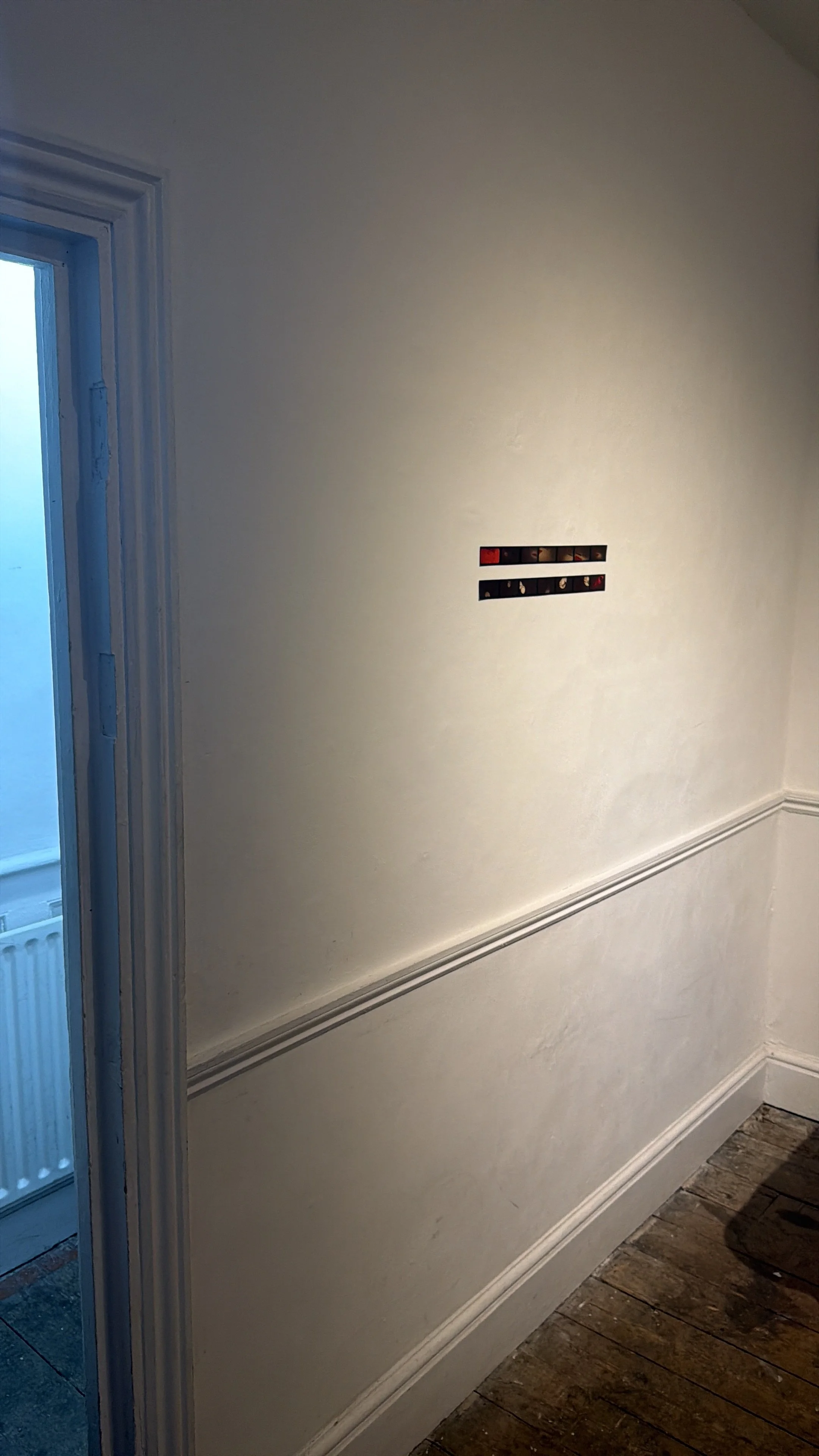 Empty cream-colored wall with a small rectangular cutout and decorative molding near the bottom, adjacent to a door with frosted glass.