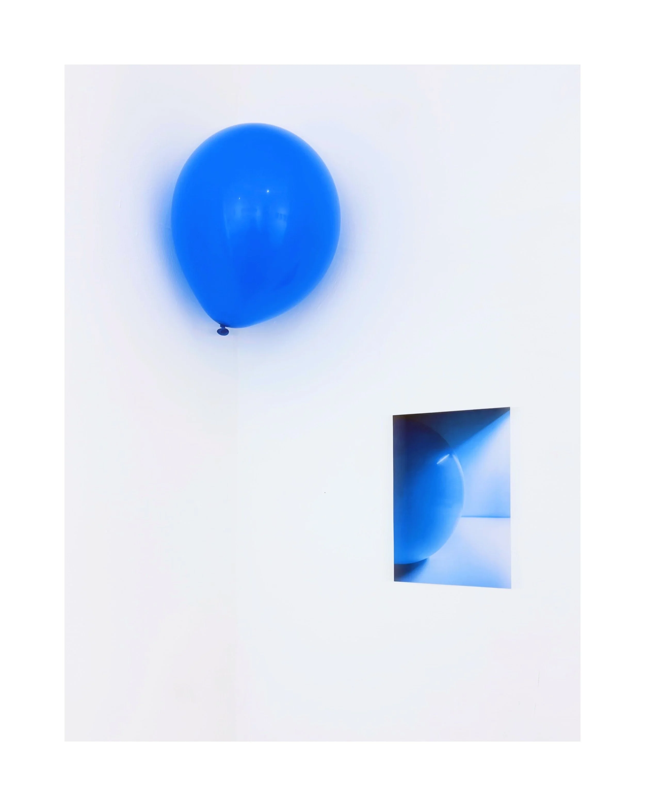 A glossy blue balloon floating against a white background, with a smaller reflected image of the balloon below.