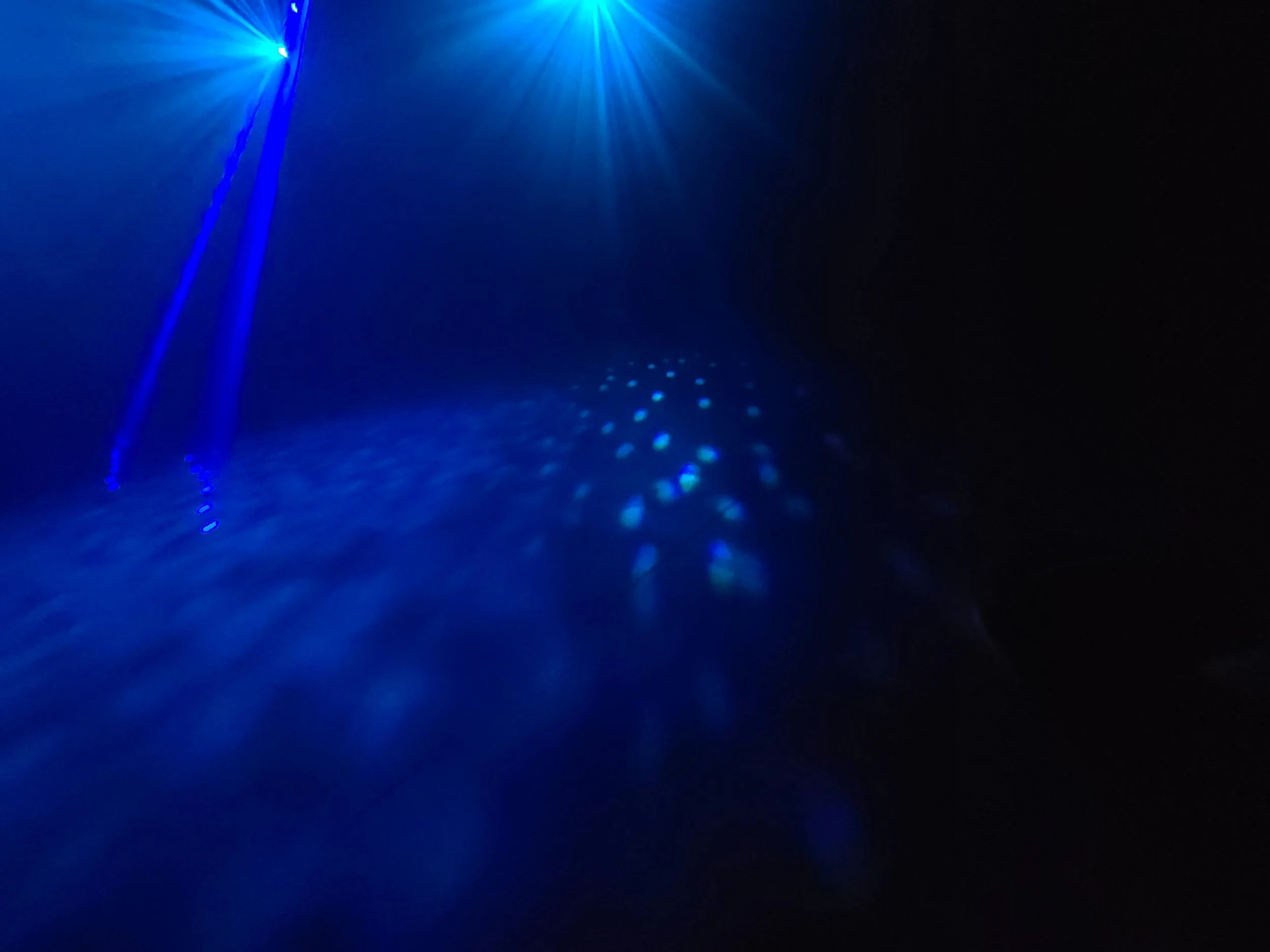 Blue laser beams projected onto a dark surface, creating a pattern of light spots and rays.