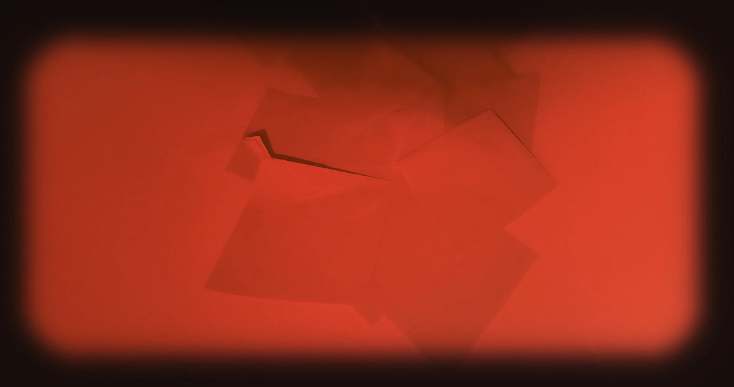 A glowing red geometric shape with sharp edges, surrounded by a dark background, with a soft gradient glow around it.